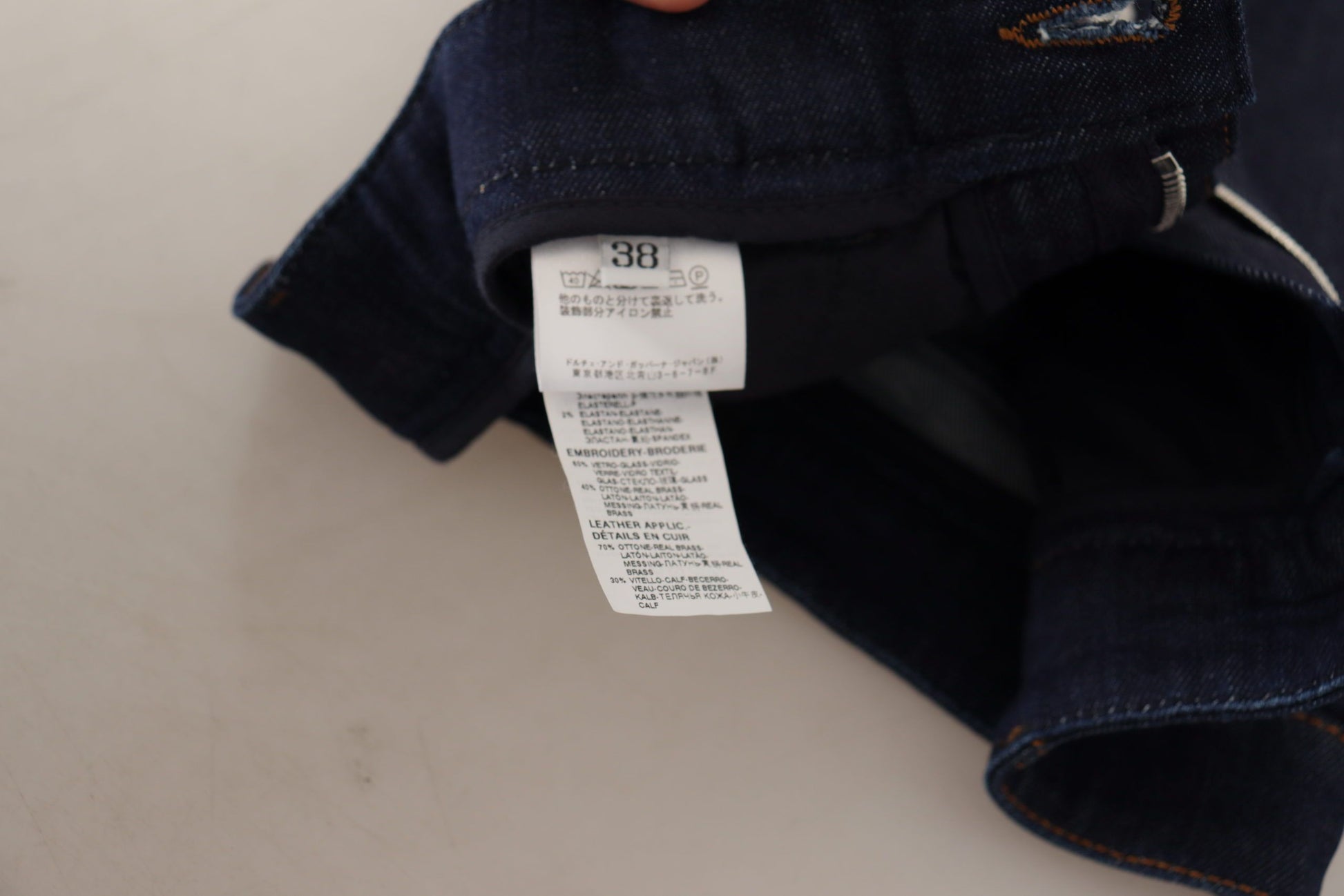 Blue denim jeans on a white surface with a price tag attached to the waistband
