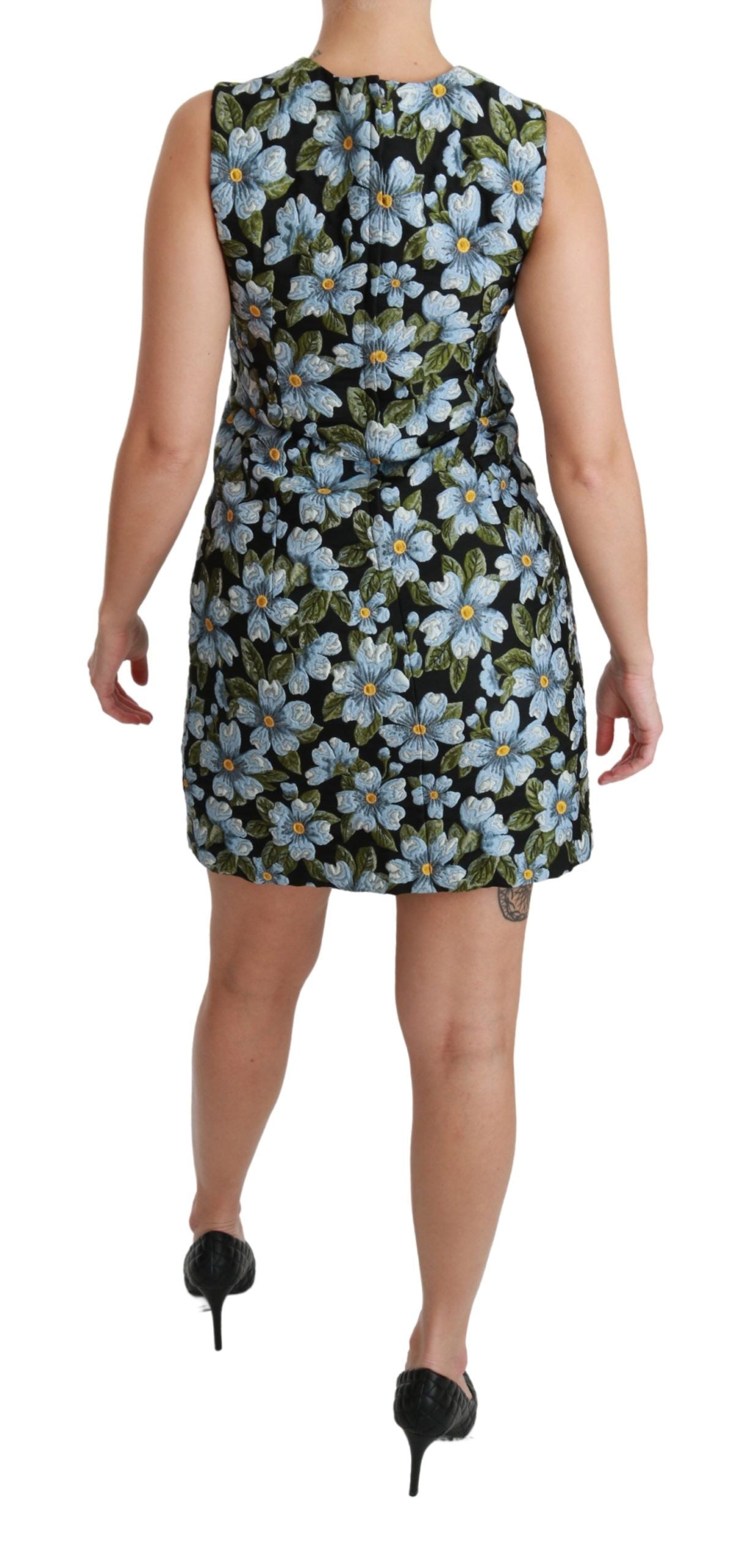 A woman wearing a blue floral brocade dress with short sleeves and a shift silhouette