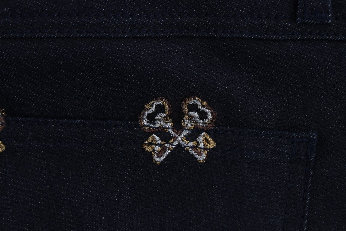 A close-up of a denim jacket with a decorative embroidery on the left chest area. The embroidery features two interlockin
