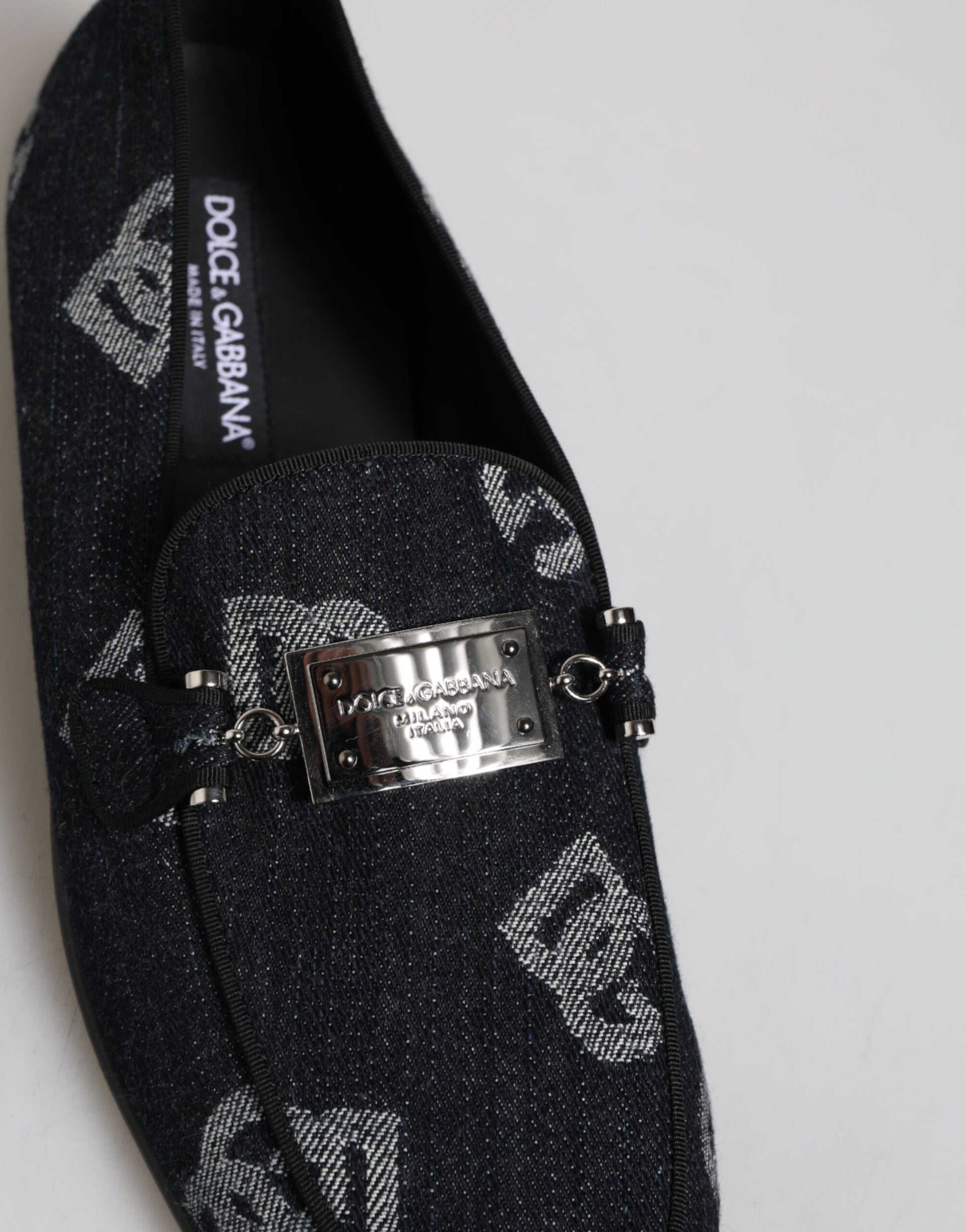 A pair of blue loafers with a logo on the side, featuring a silver buckle