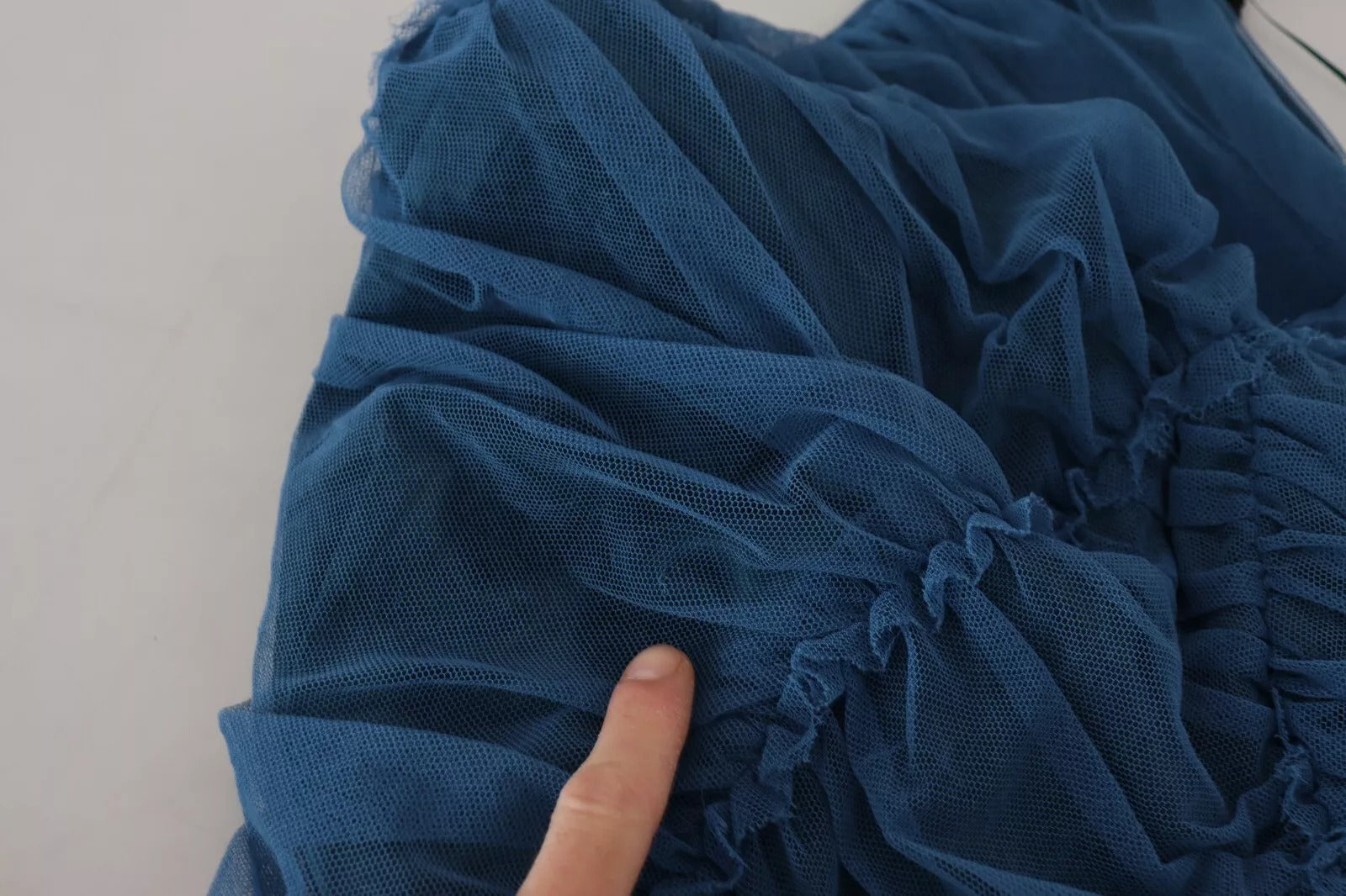 A blue mesh trim ruched tulle sheath dress with a hand touching the fabric