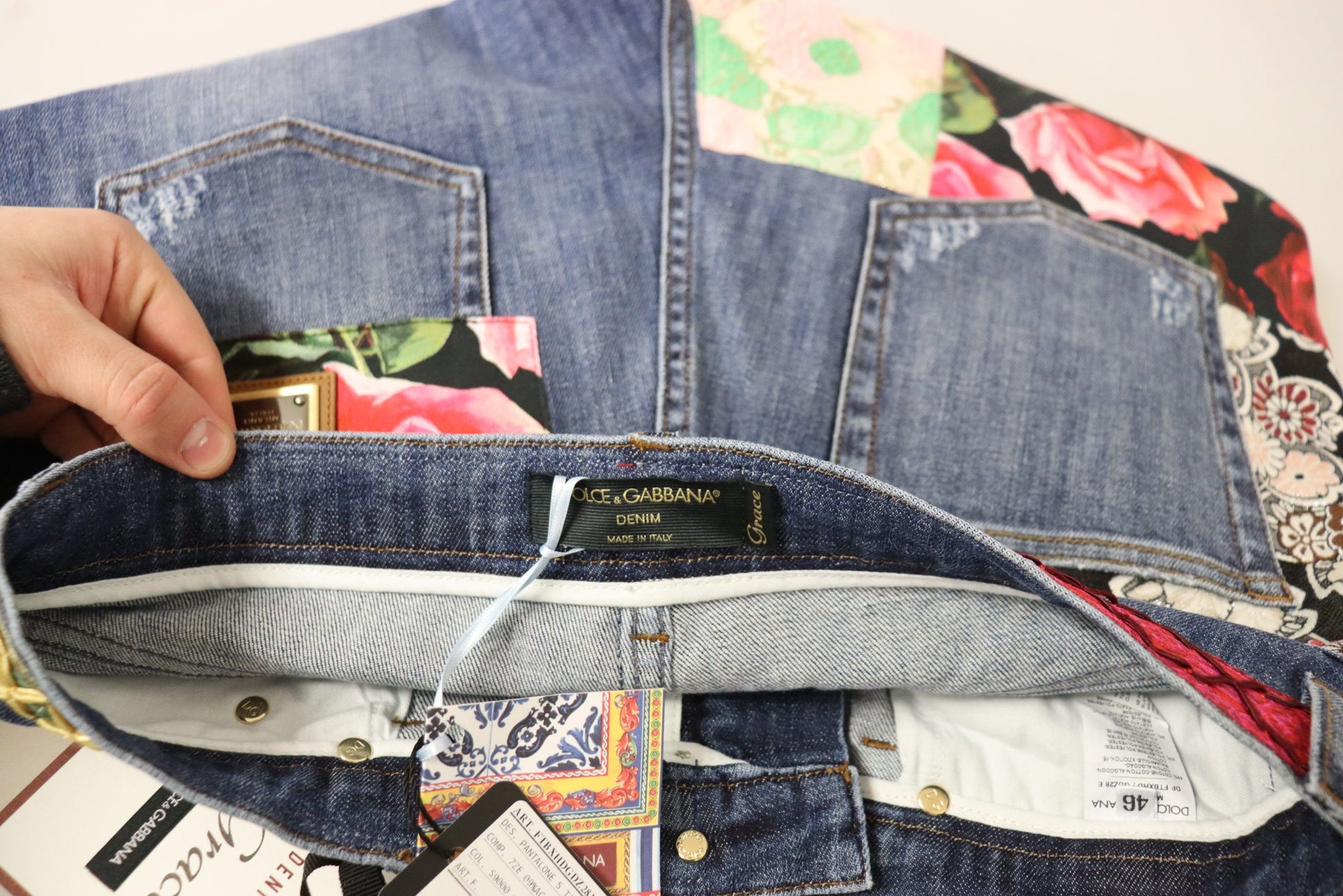 Hand holding open jeans pocket revealing tags inside