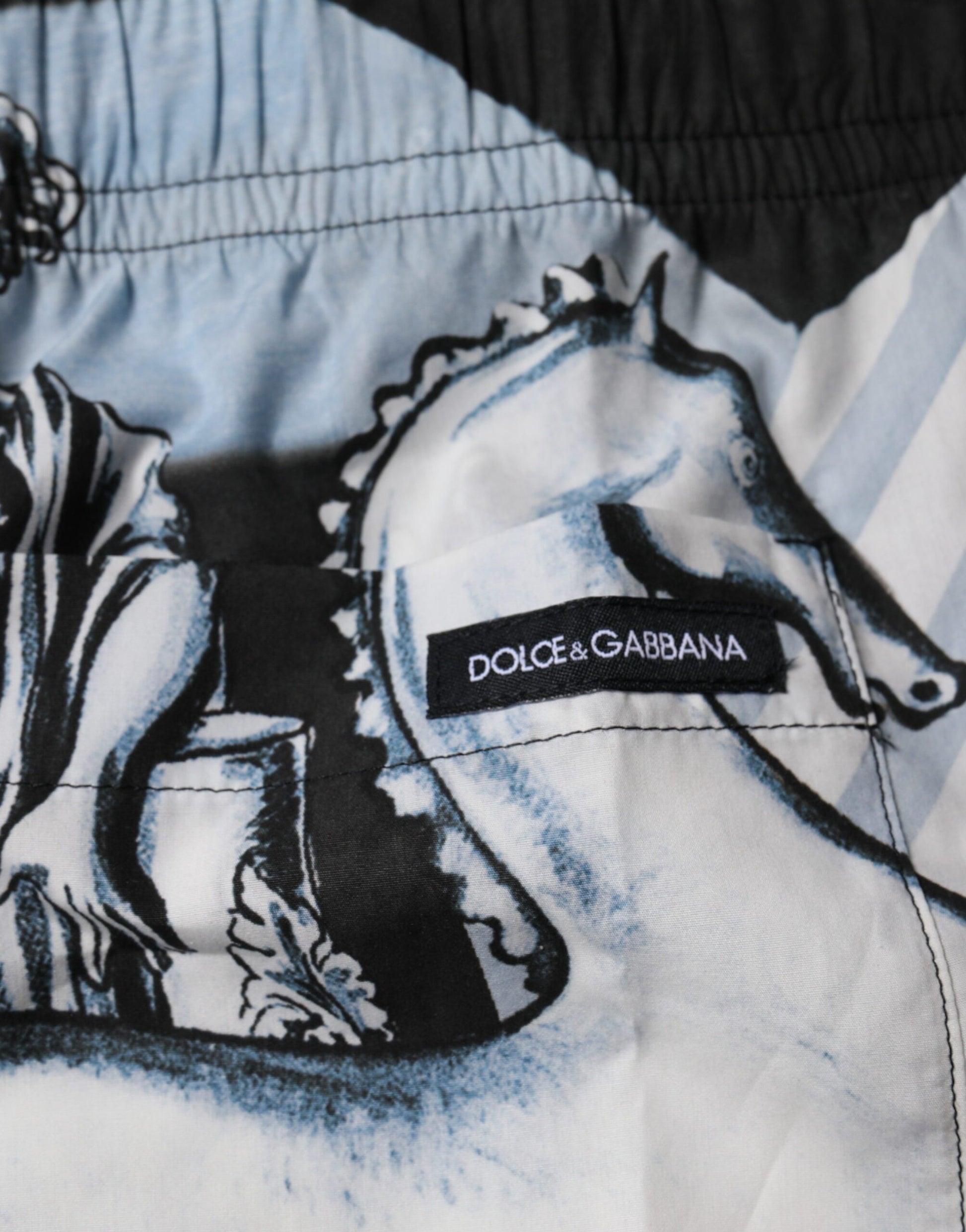 A pair of blue shorts with a statue print, featuring the Dolce & Gabbana logo on the waistband