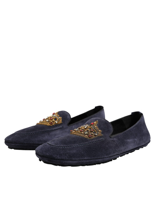 A pair of blue suede loafers with gold embellishments and a crown logo