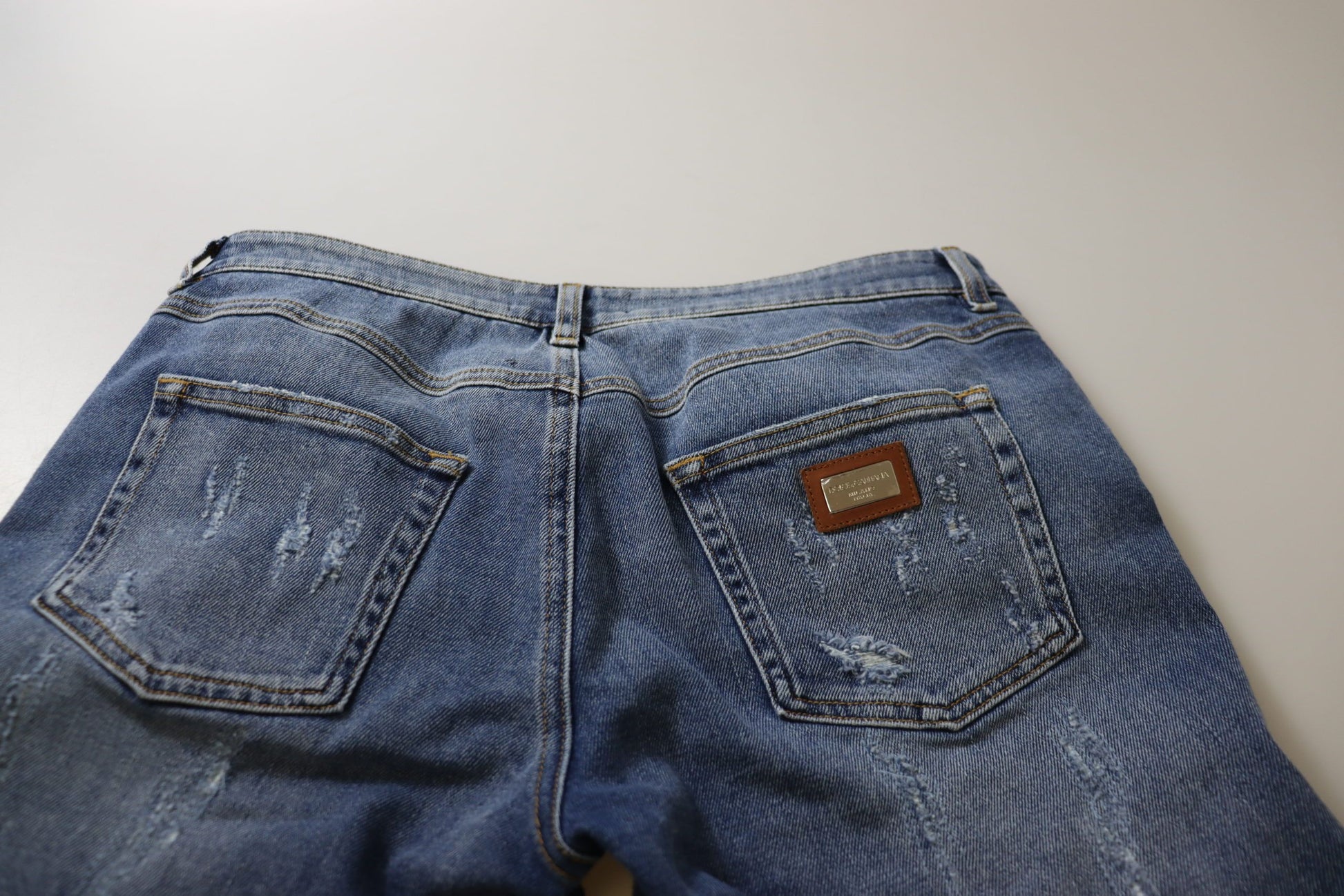 Pair of blue denim jeans with front pockets and a brown leather patch on the right side
