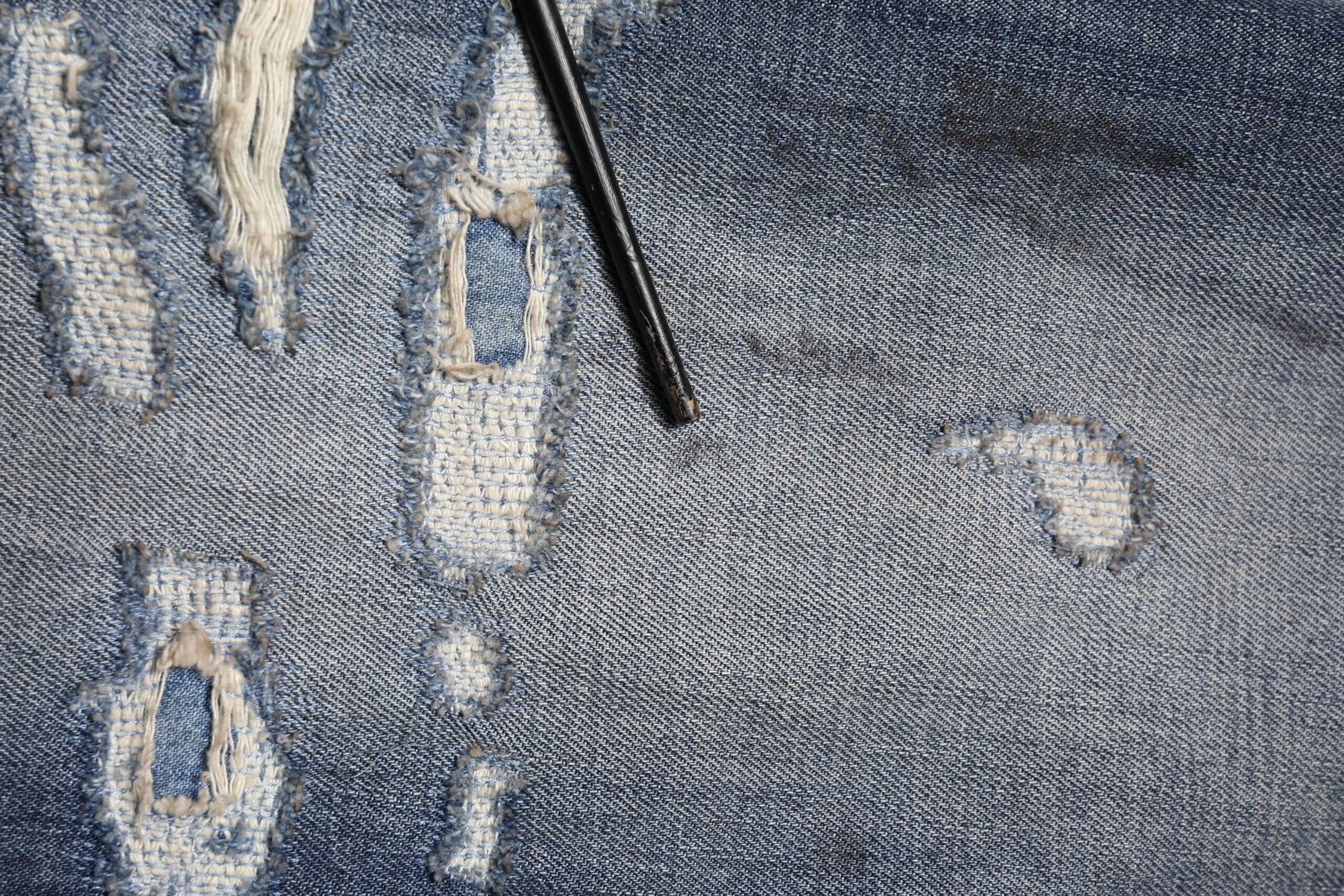 Denim jeans with distressed areas and a black pen marking them