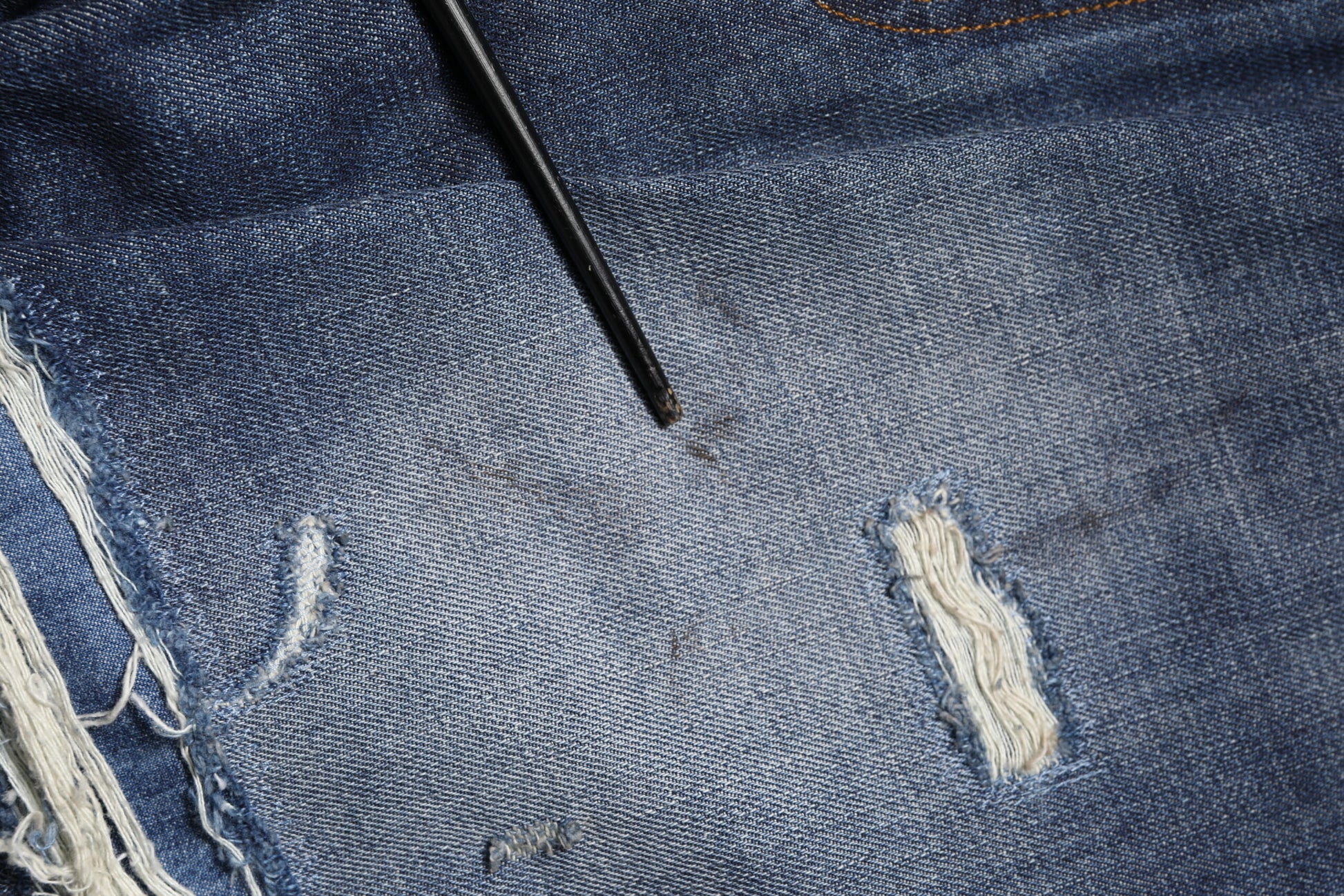 Blue denim jeans with a hole in the knee area