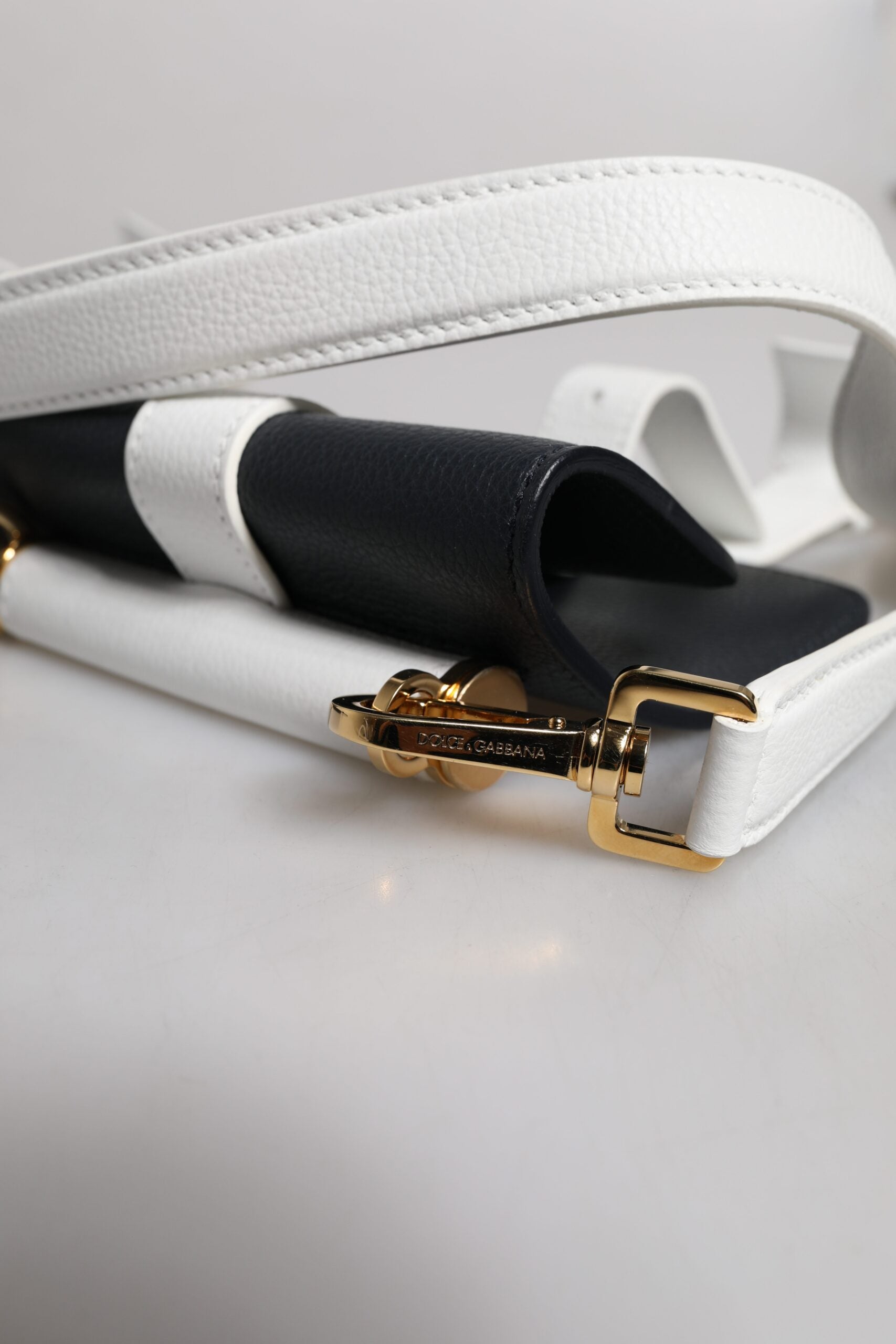 White leather handbag with black trim and gold hardware