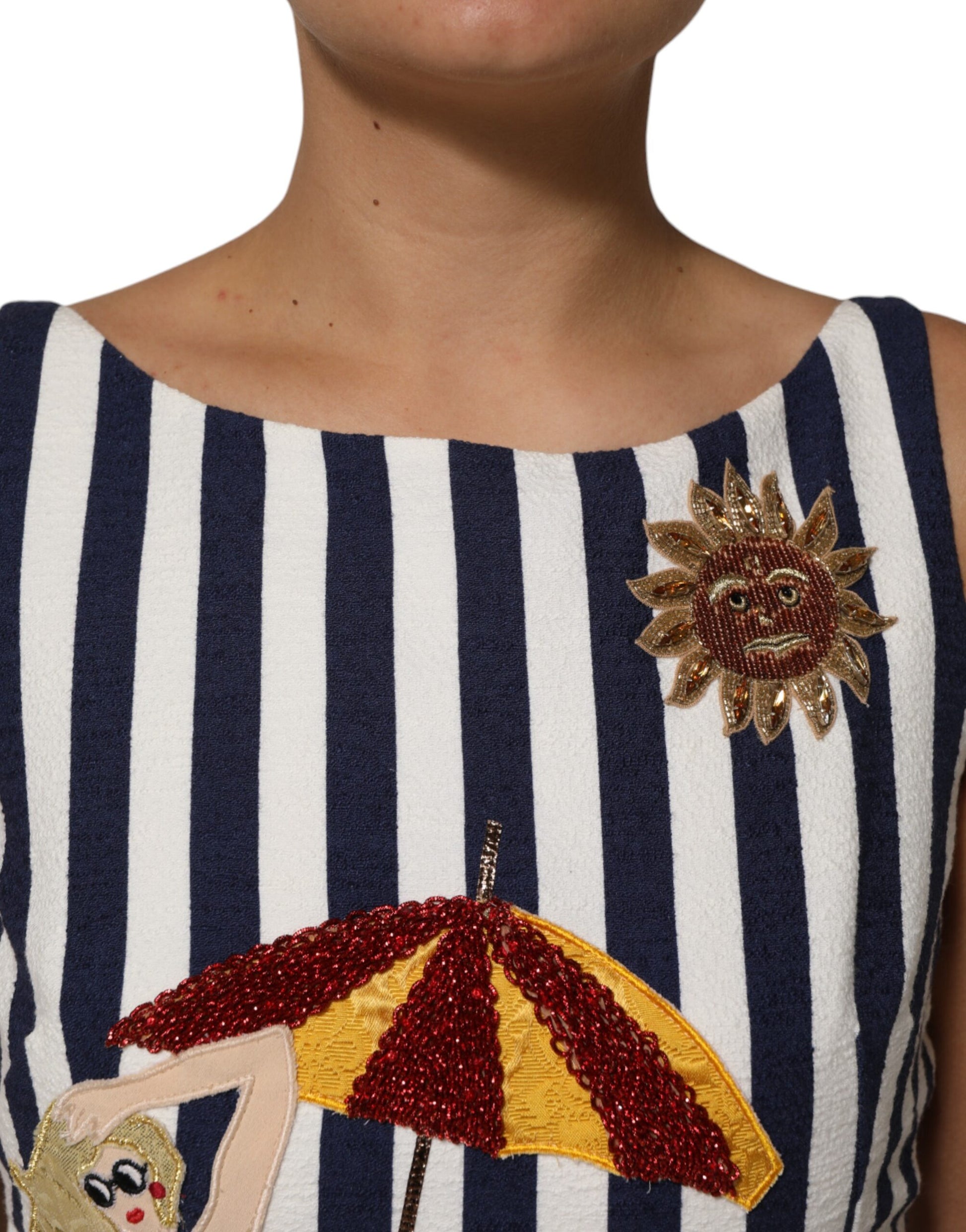 A blue and white striped dress with embroidery of a sun, umbrella, and woman
