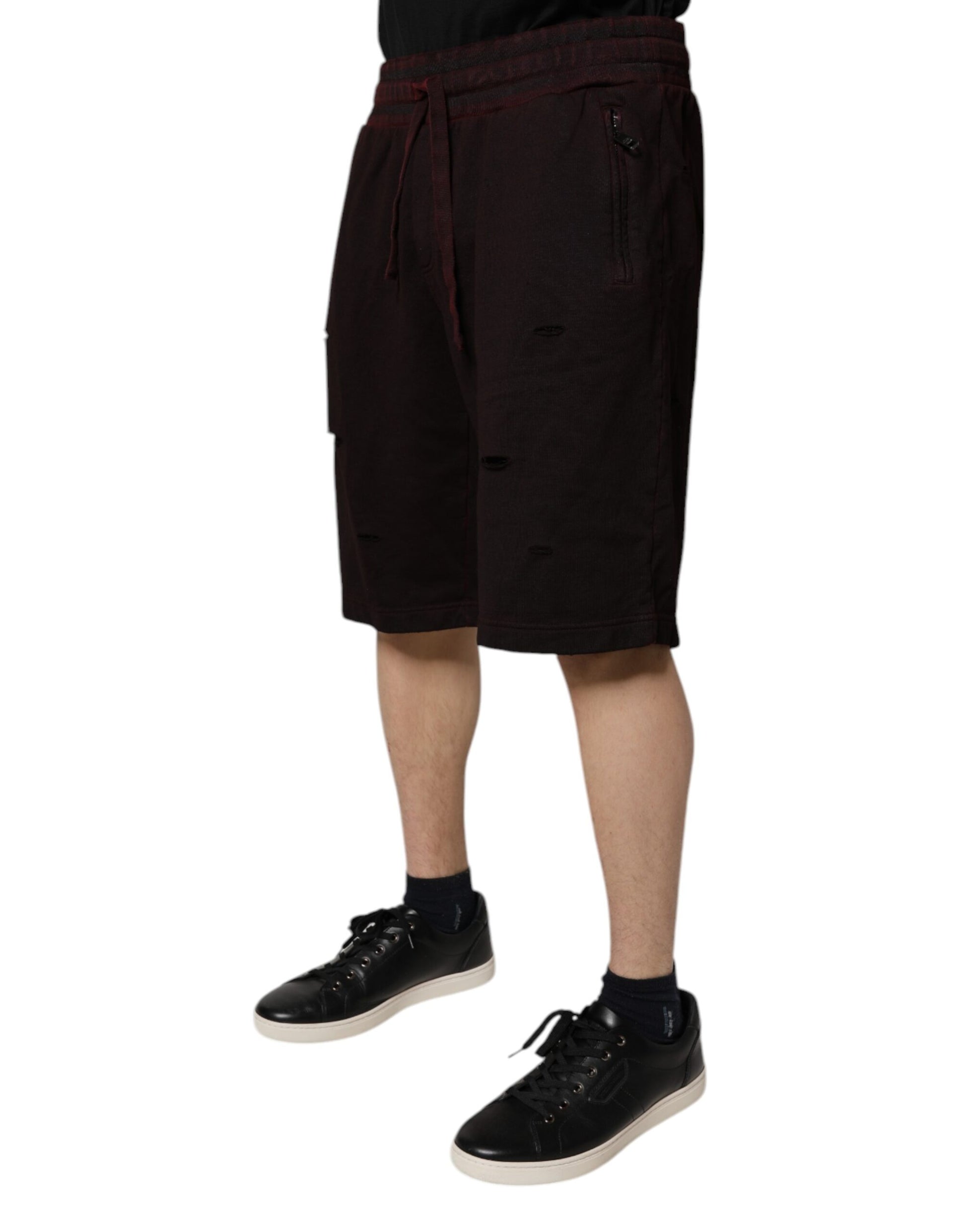 A pair of black shorts with red trim, featuring the brand name "Dolce & Gabbana" on the waistband. They are m