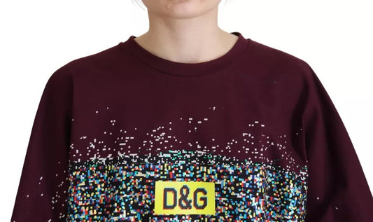 Woman wearing maroon sweatshirt with yellow D&G logo