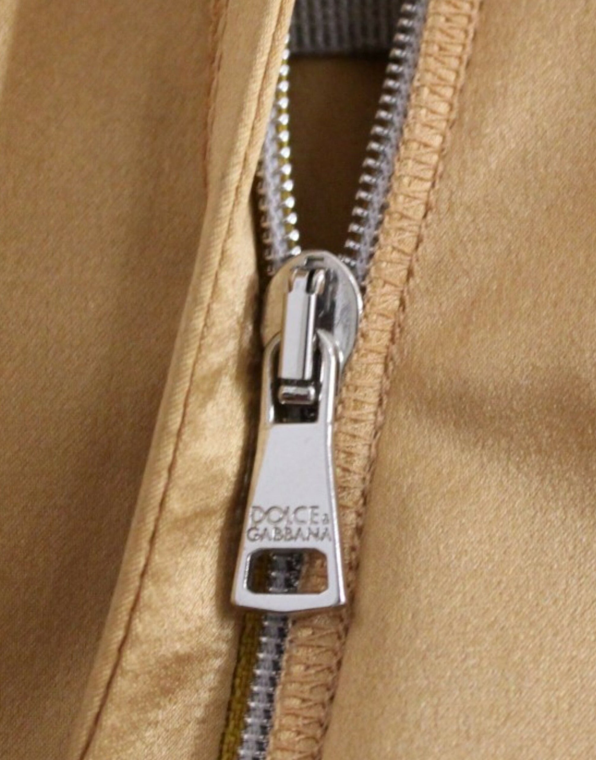 Silver zipper pull on tan fabric