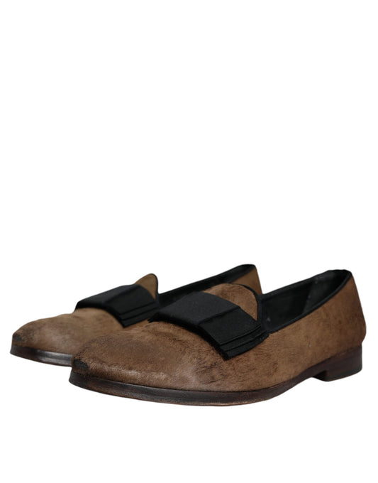 A pair of brown leather loafers with black straps, featuring a calf hair texture