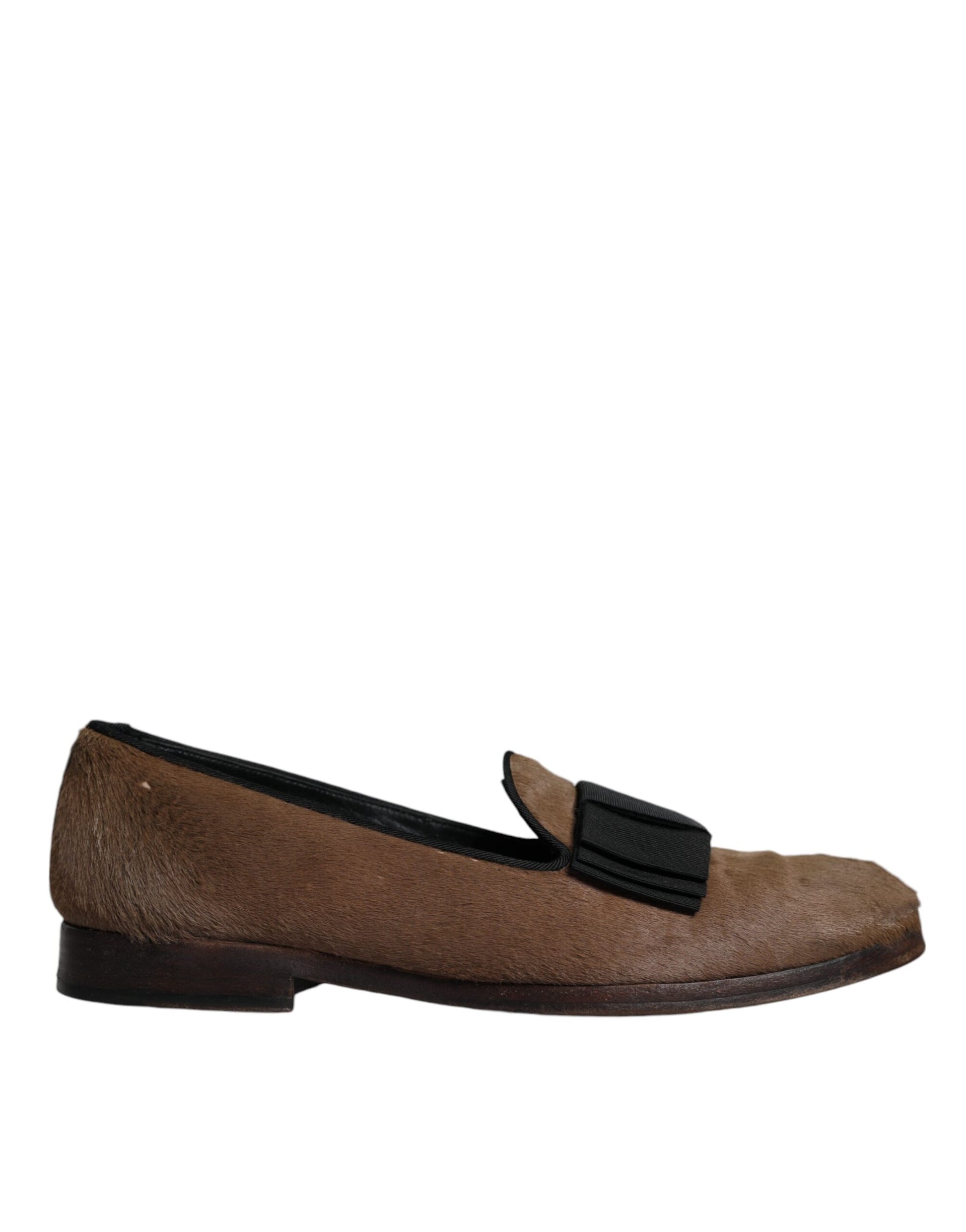 A pair of brown leather loafers with black straps, featuring a stitched design and a low heel
