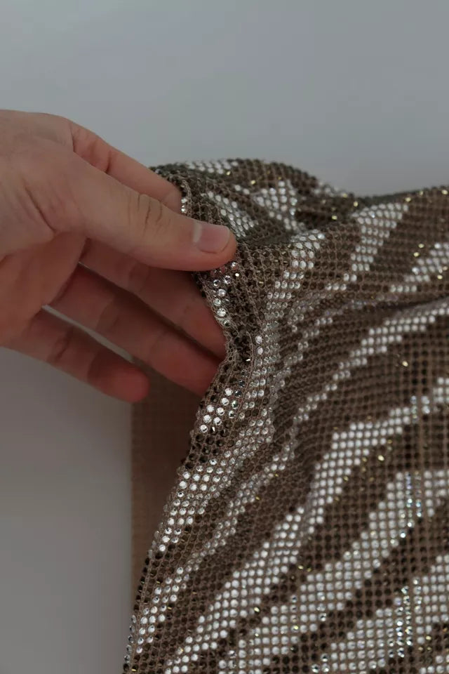 Hand holding a brown crystal shift mini zebra silver dress with sequins and ruffles