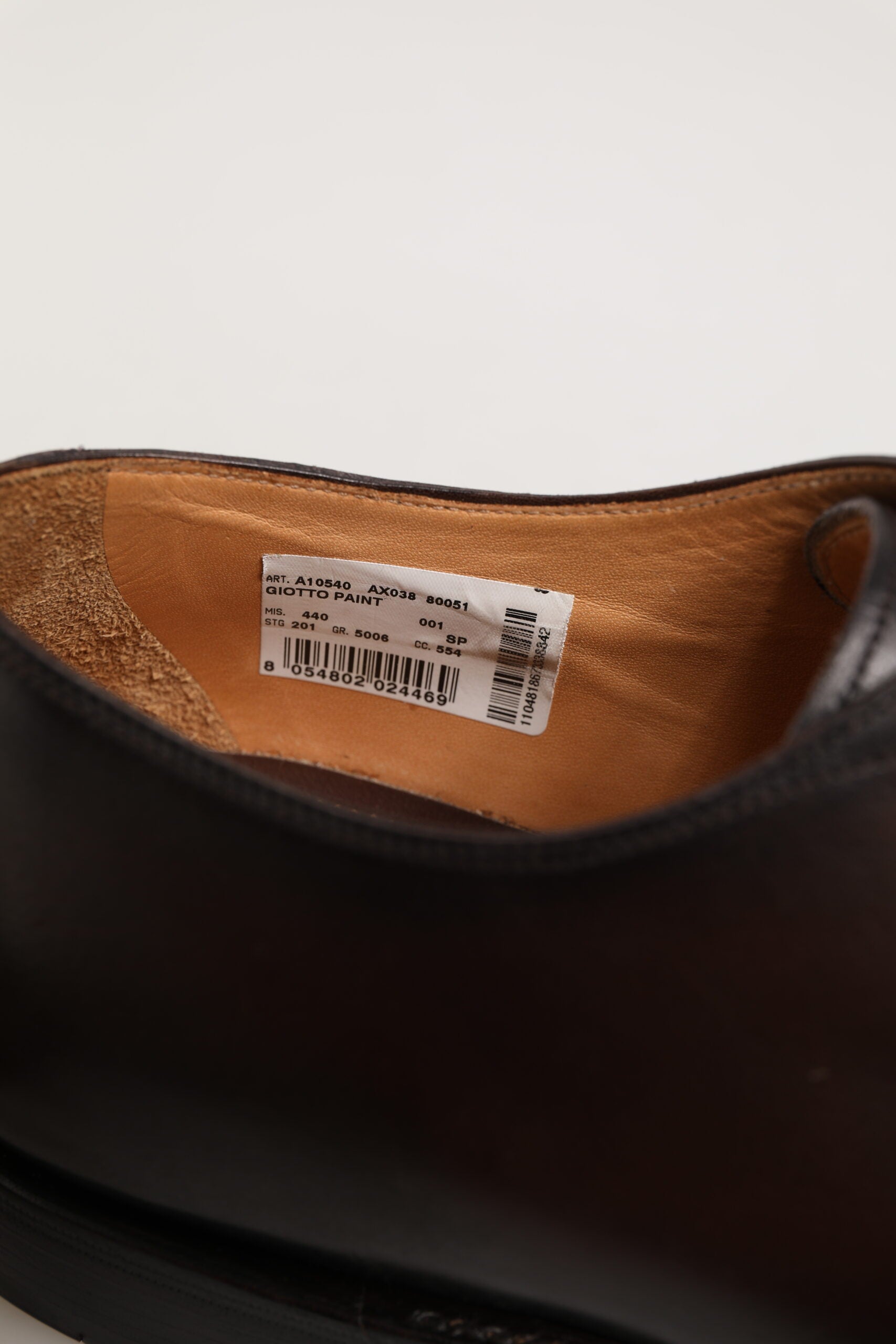 A brown leather lace up dress shoe with a label on the inside