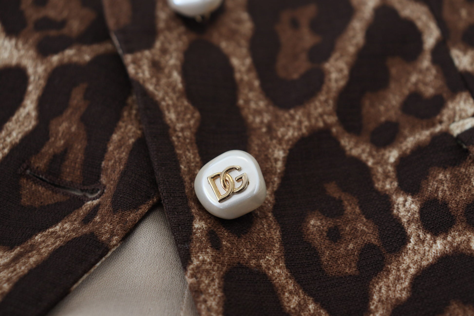Leopard print fabric with a white button featuring a gold letter 'D'