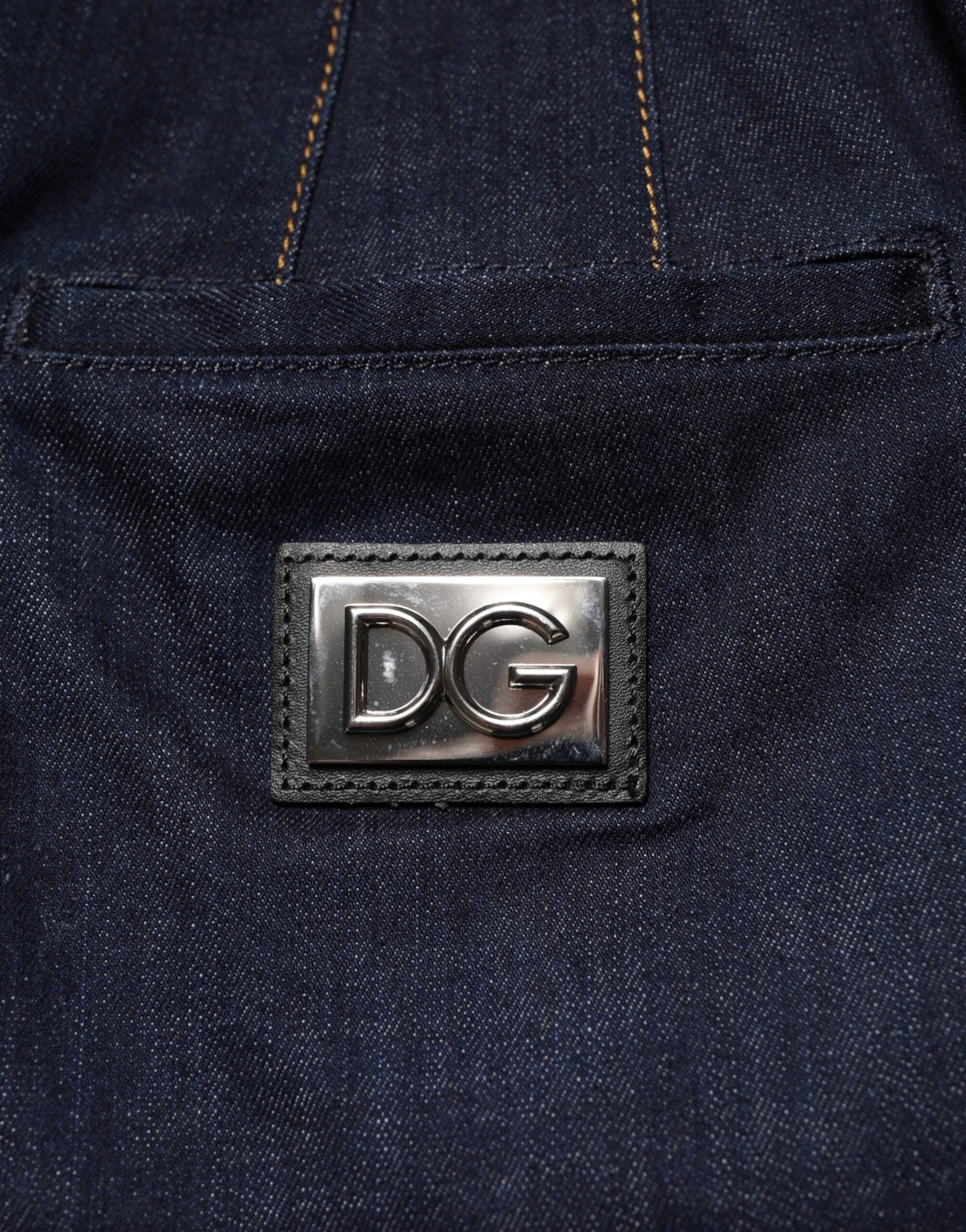Pair of blue jeans with a silver logo on the front pocket