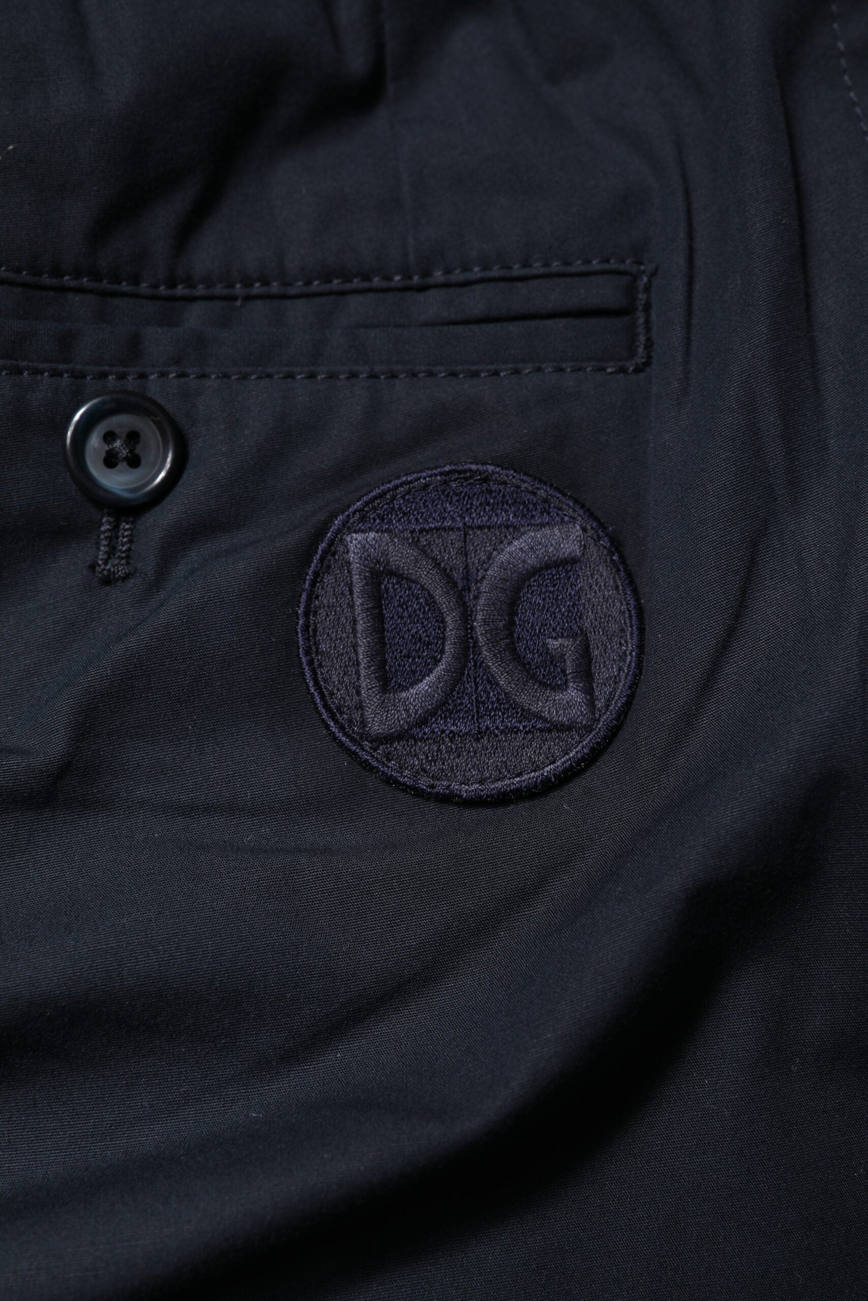A pair of dark blue cotton bermuda shorts with the Dolce & Gabbana logo embroidered on the left leg