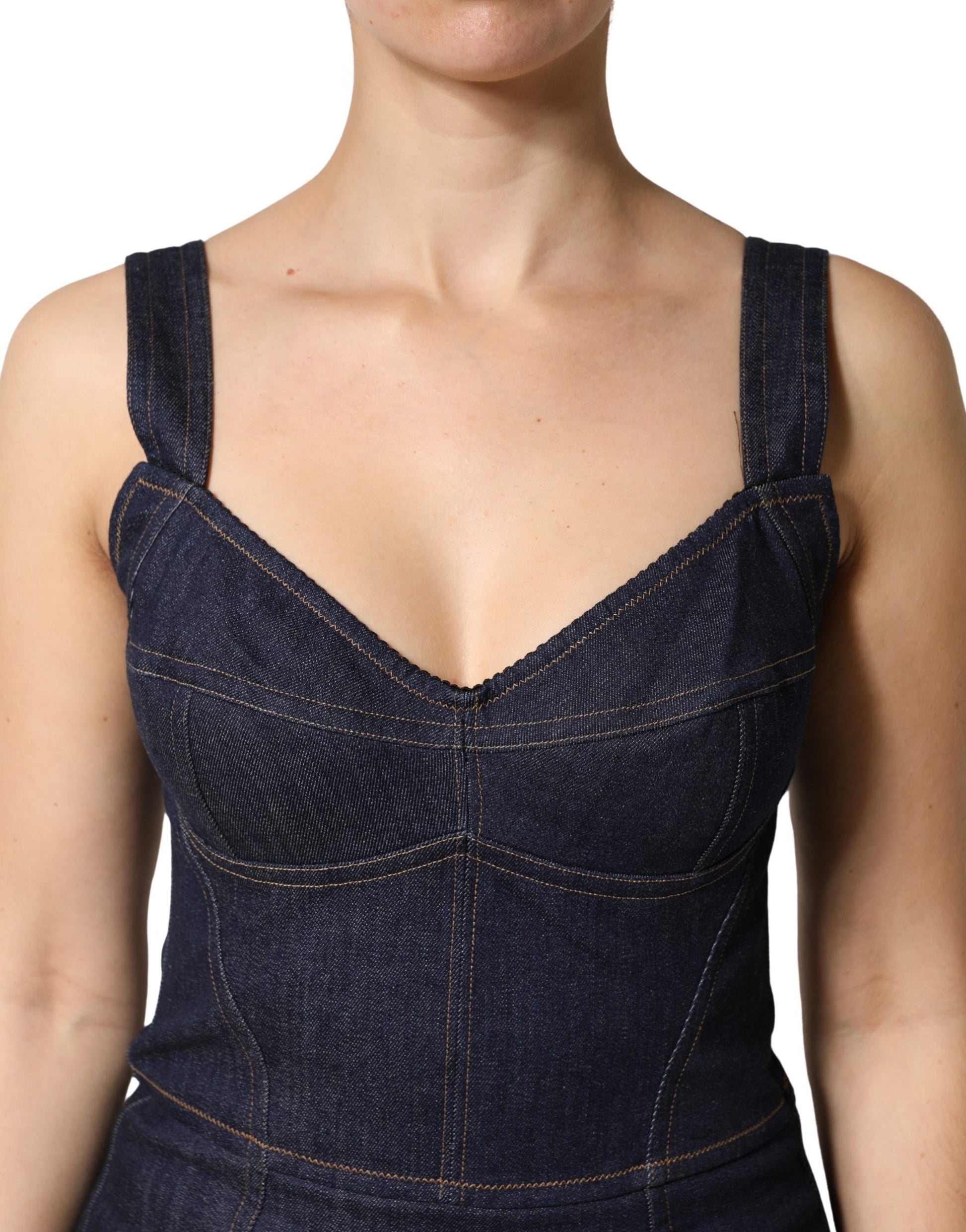 A woman wearing a dark blue denim sheath midi dress with a plunging neckline