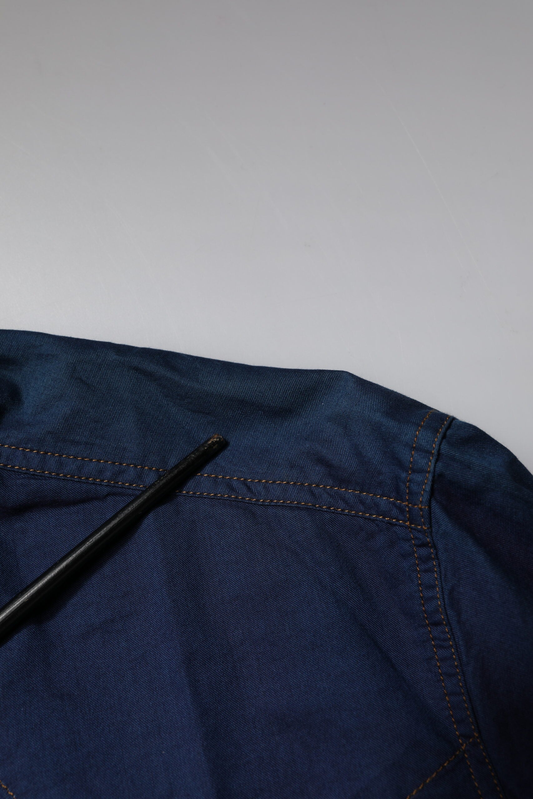 A dark blue denim shirt with a gold zipper and button detailing