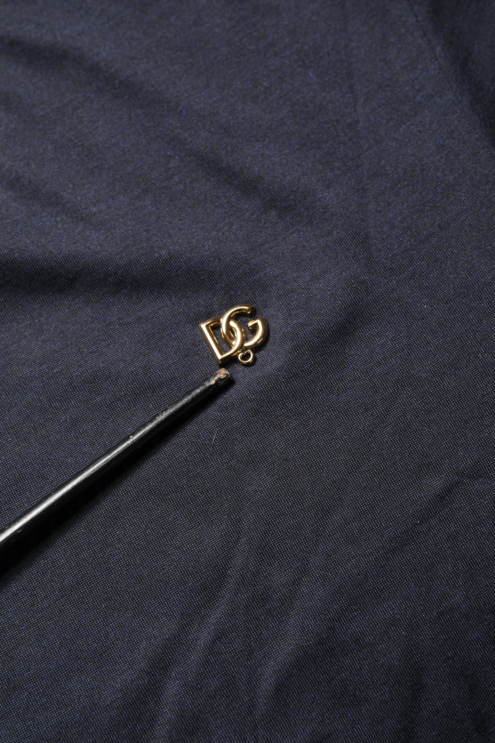 Small gold embroidery needle on blue fabric