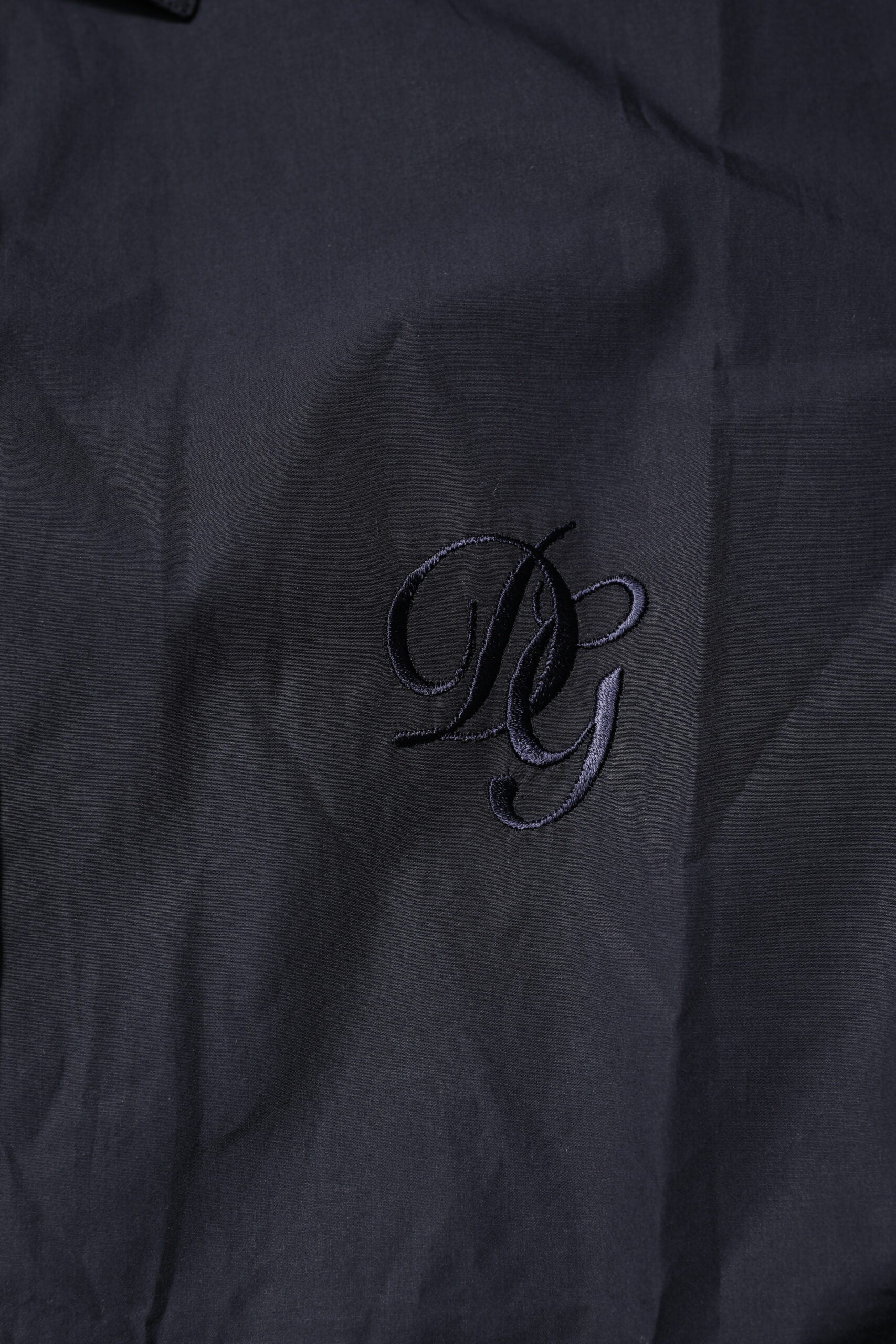 A dark blue dress shirt with a monogrammed logo on the left chest