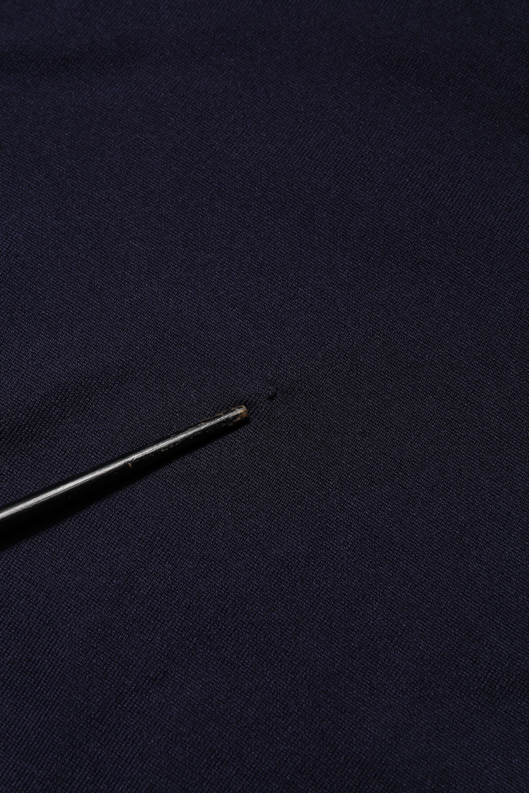 Small black pin on blue fabric