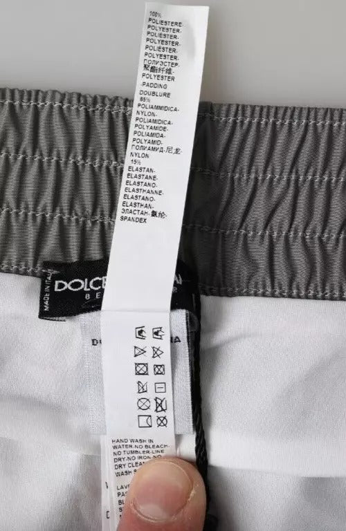 A pair of dark gray polyester beachwear shorts with a label