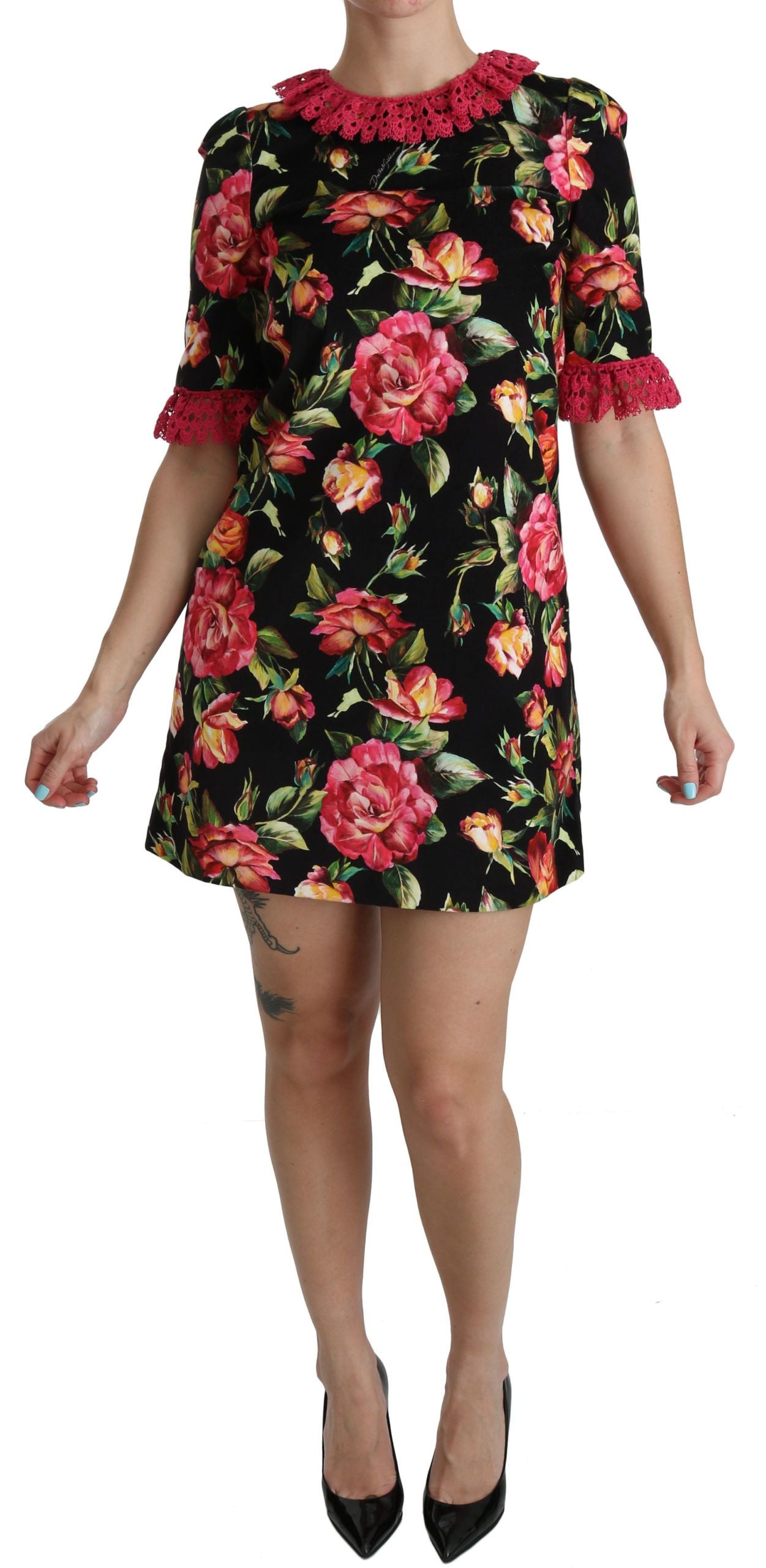 A woman wearing a black and pink floral lace dress with ruffled sleeves