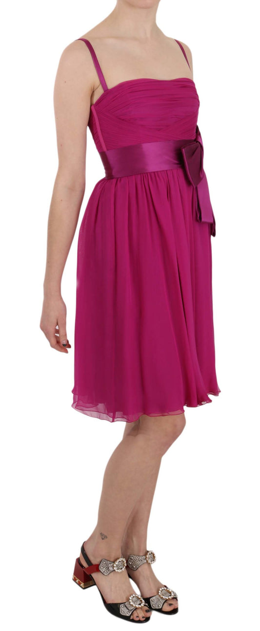 A sleeveless pink dress with a bow detail on the waist