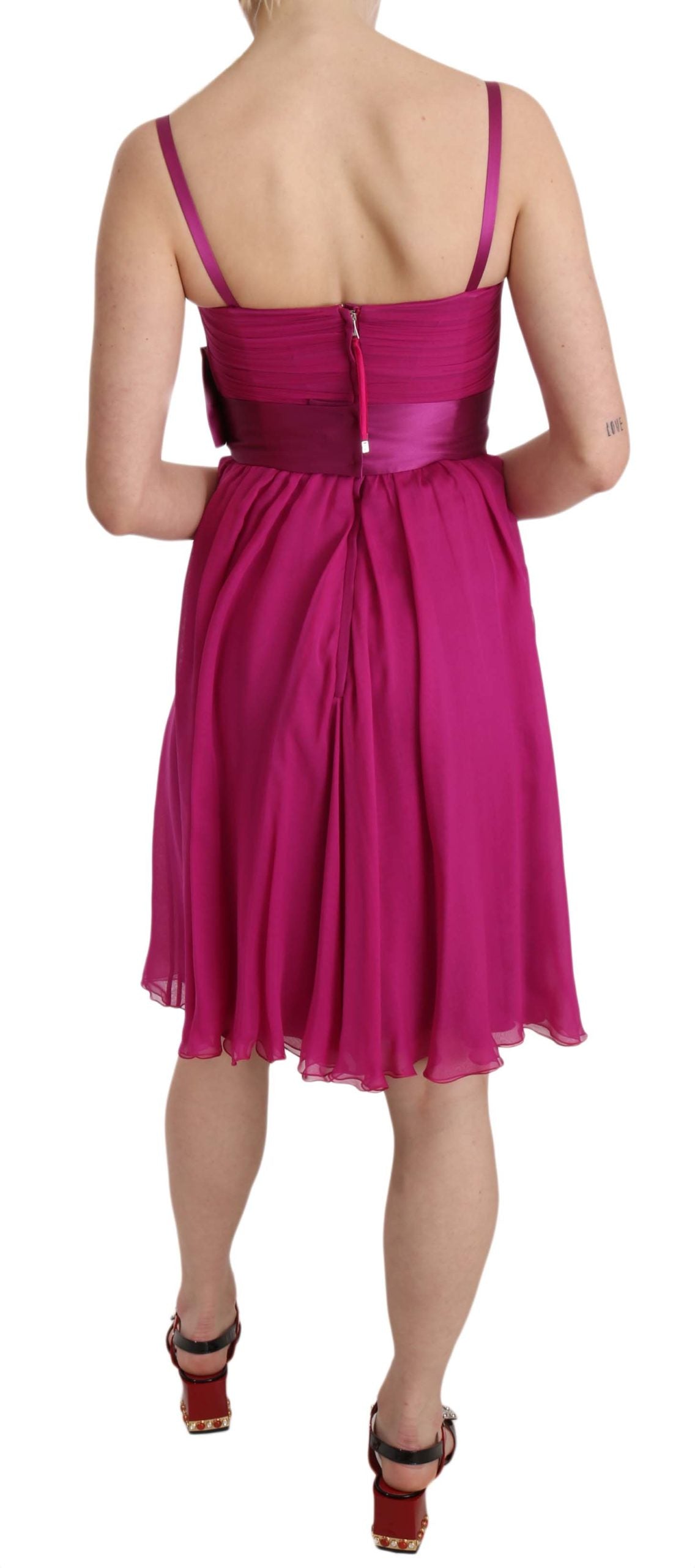 A sleeveless pink dress with a bow detail on the waist