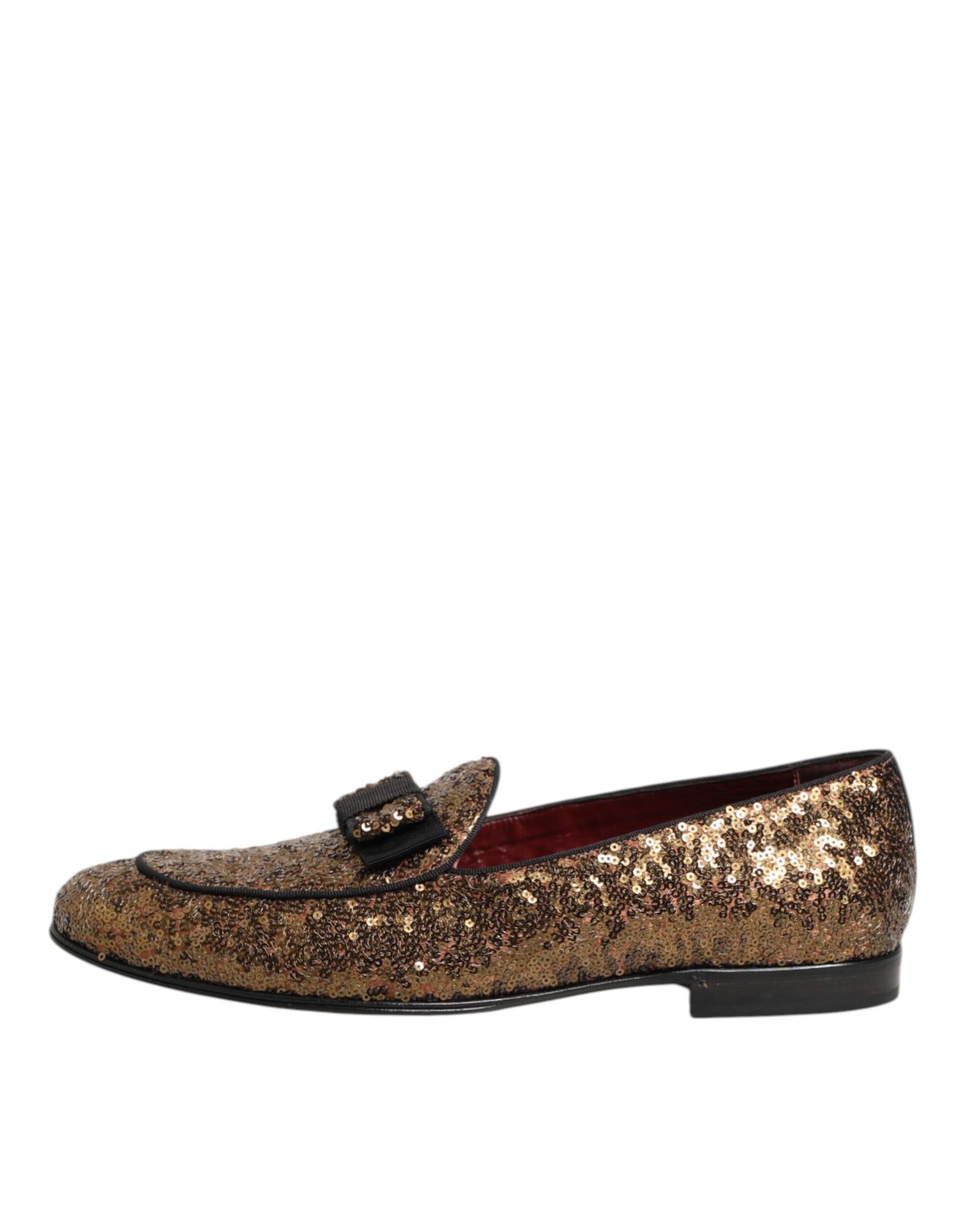 A pair of gold sequined loafers with a bow on the side, designed by Dolce & Gabbana