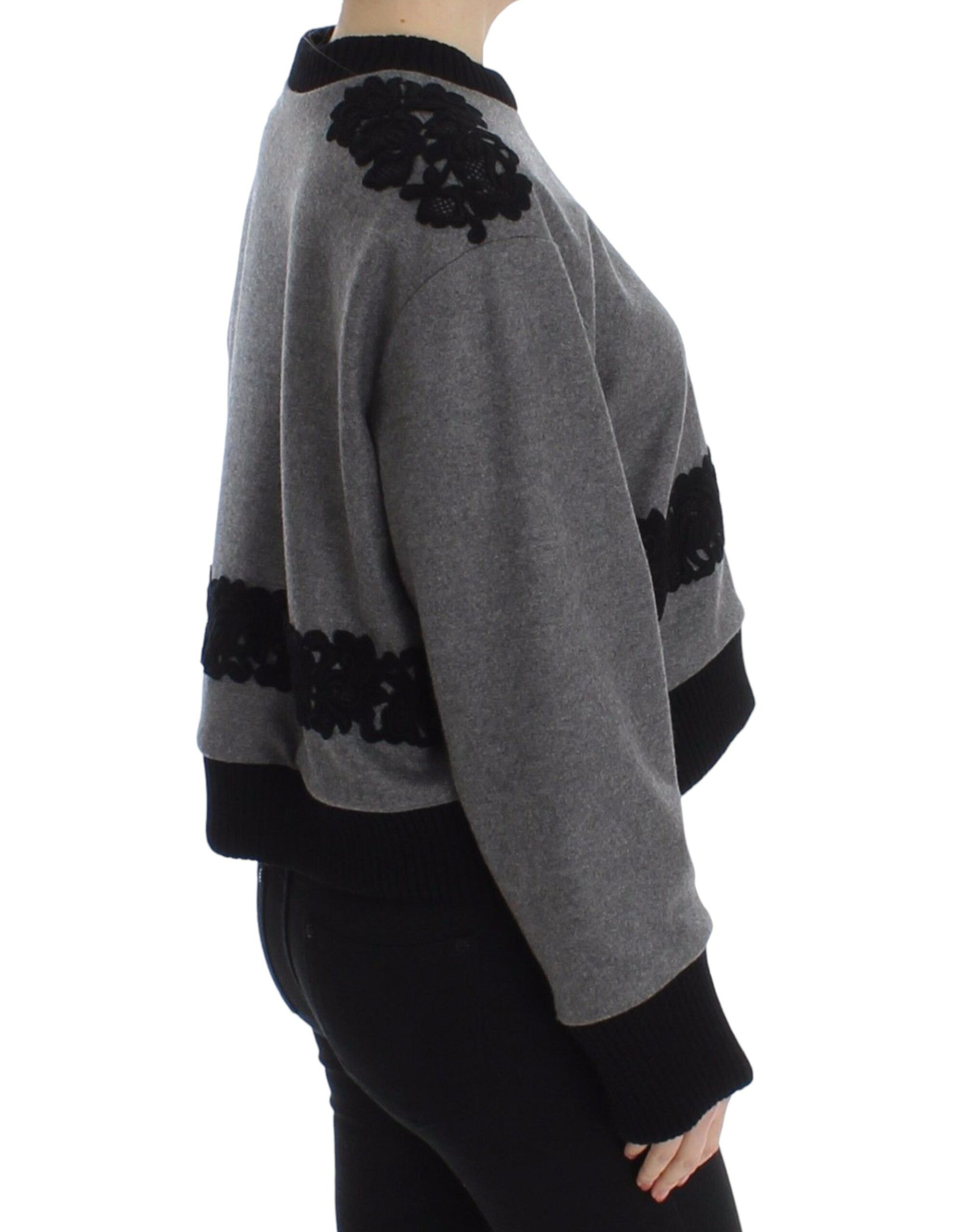 Woman wearing gray sweater with black embroidery on back