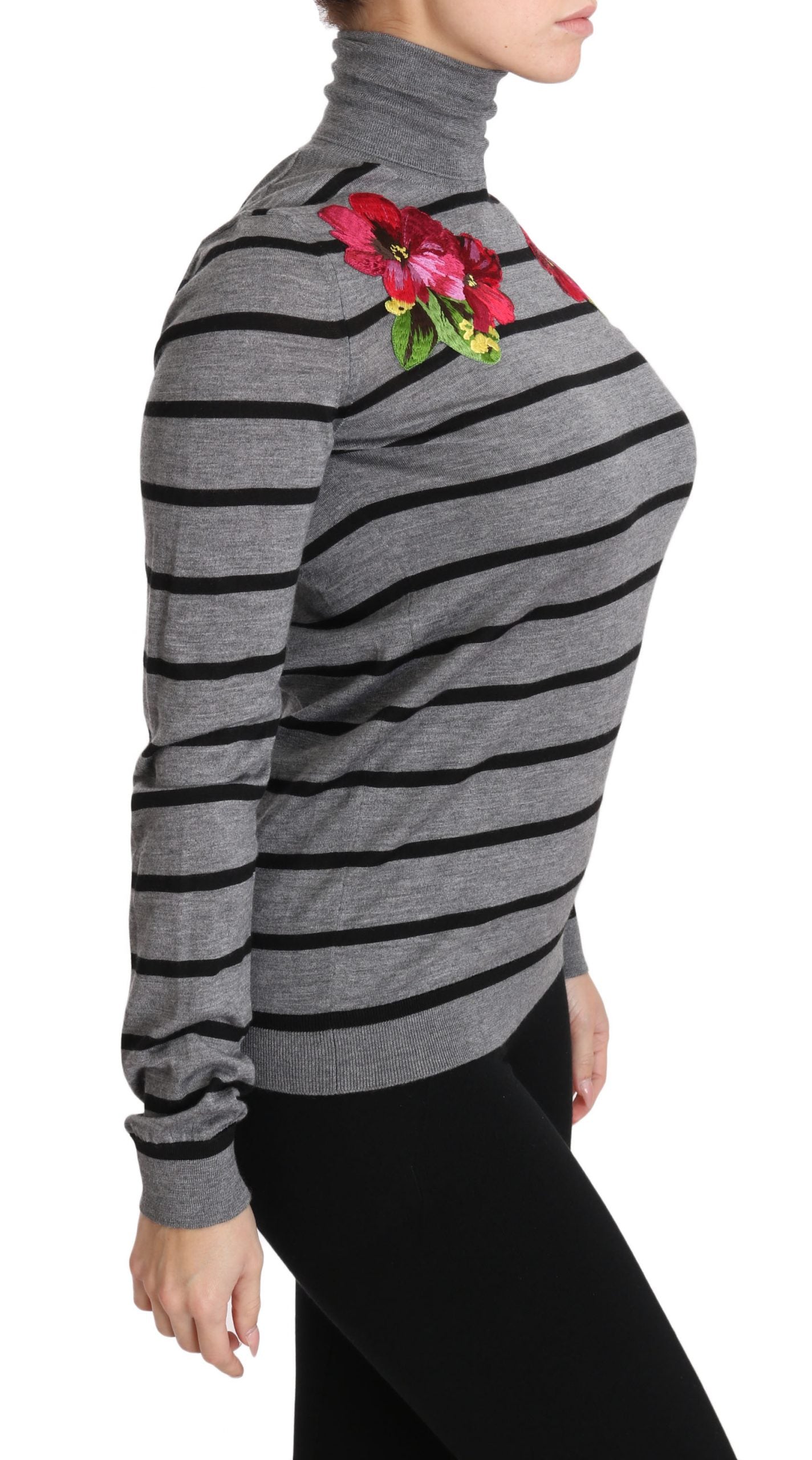 Woman wearing a black and gray striped sweater with a floral embellishment on the chest