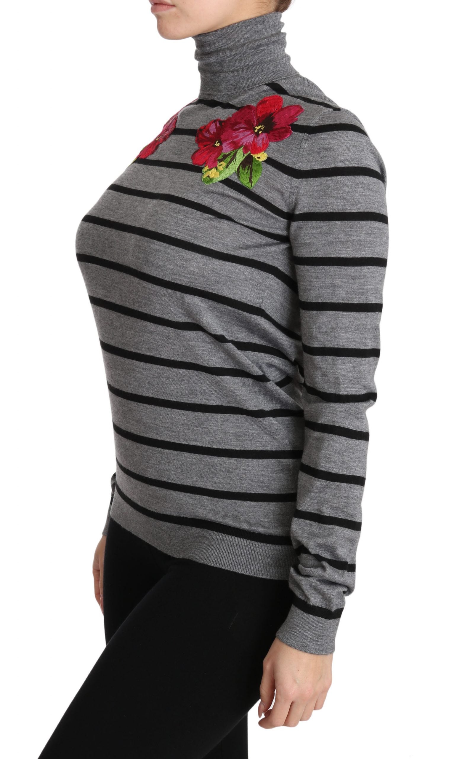Woman wearing a black and gray striped sweater with a floral embellishment on the chest