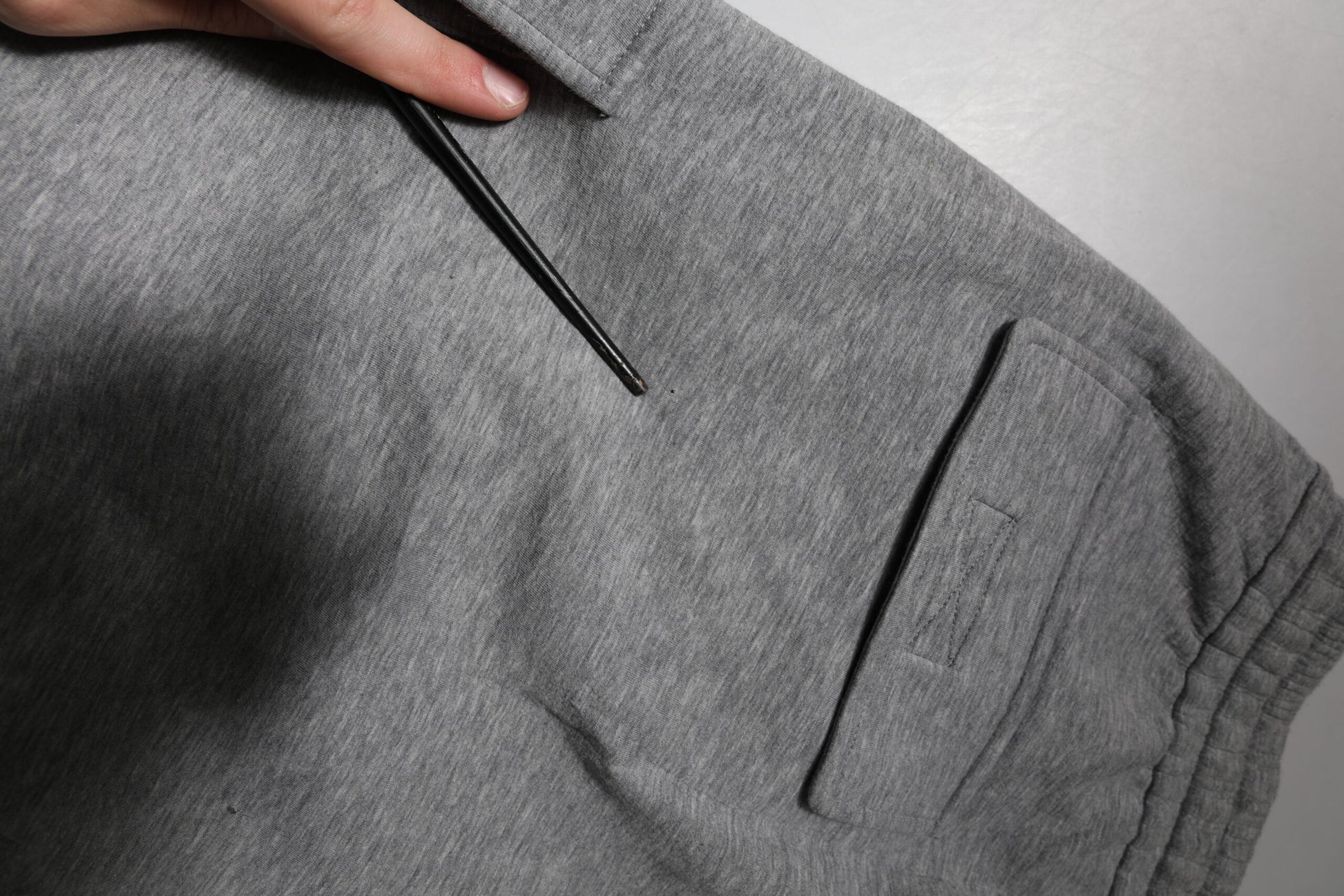 A pair of gray cotton cargo shorts with a zippered pocket on the left leg