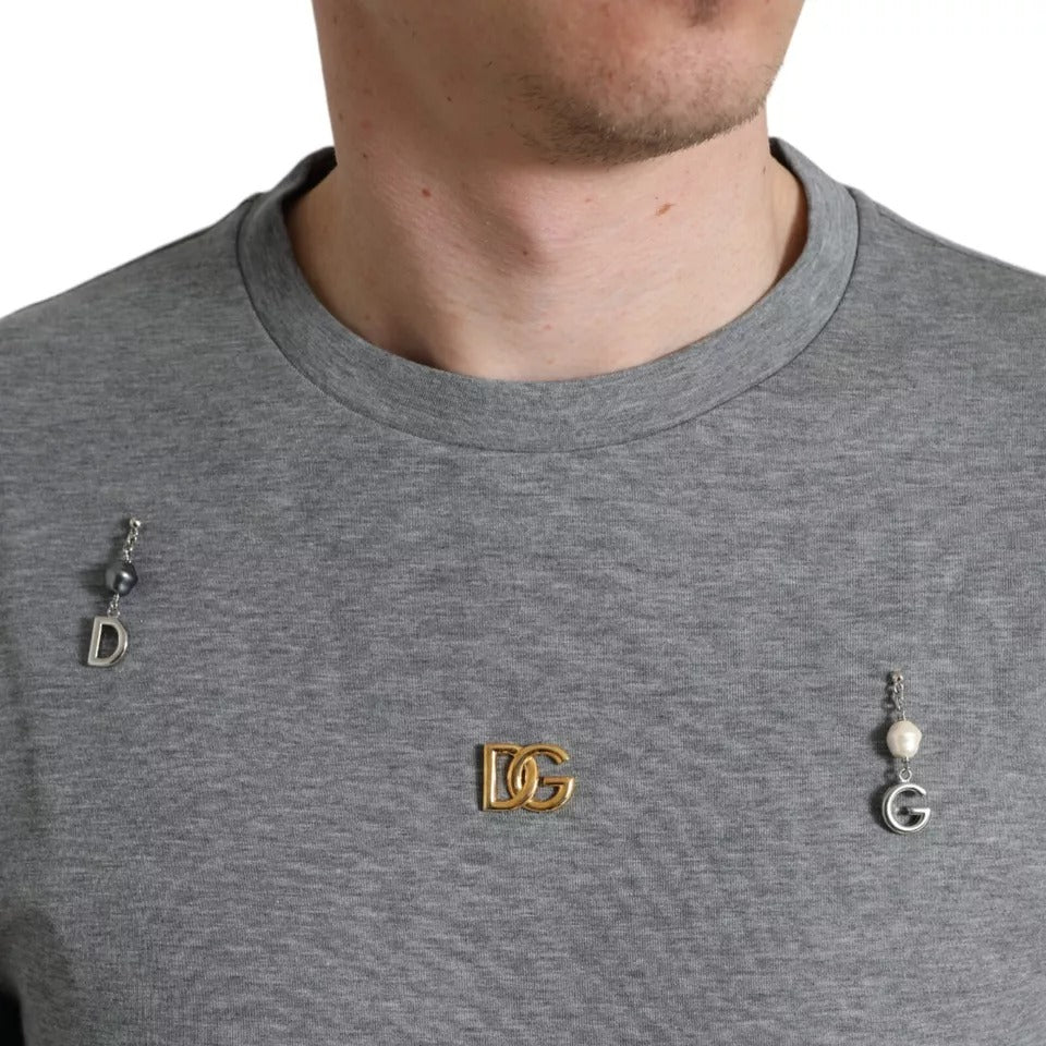 Man wearing grey shirt with earrings spelling out "DG"