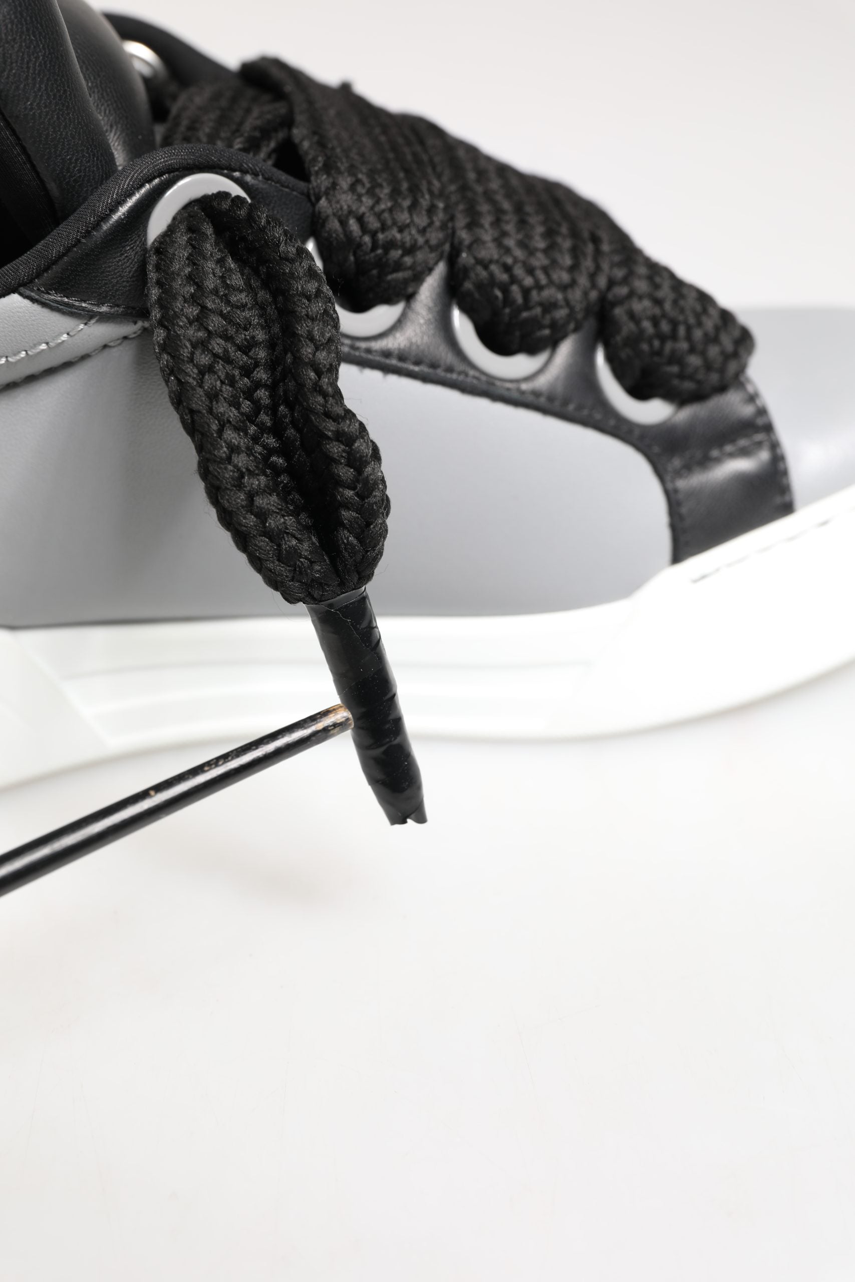 A pair of gray leather lace-up sneakers with a black knit upper