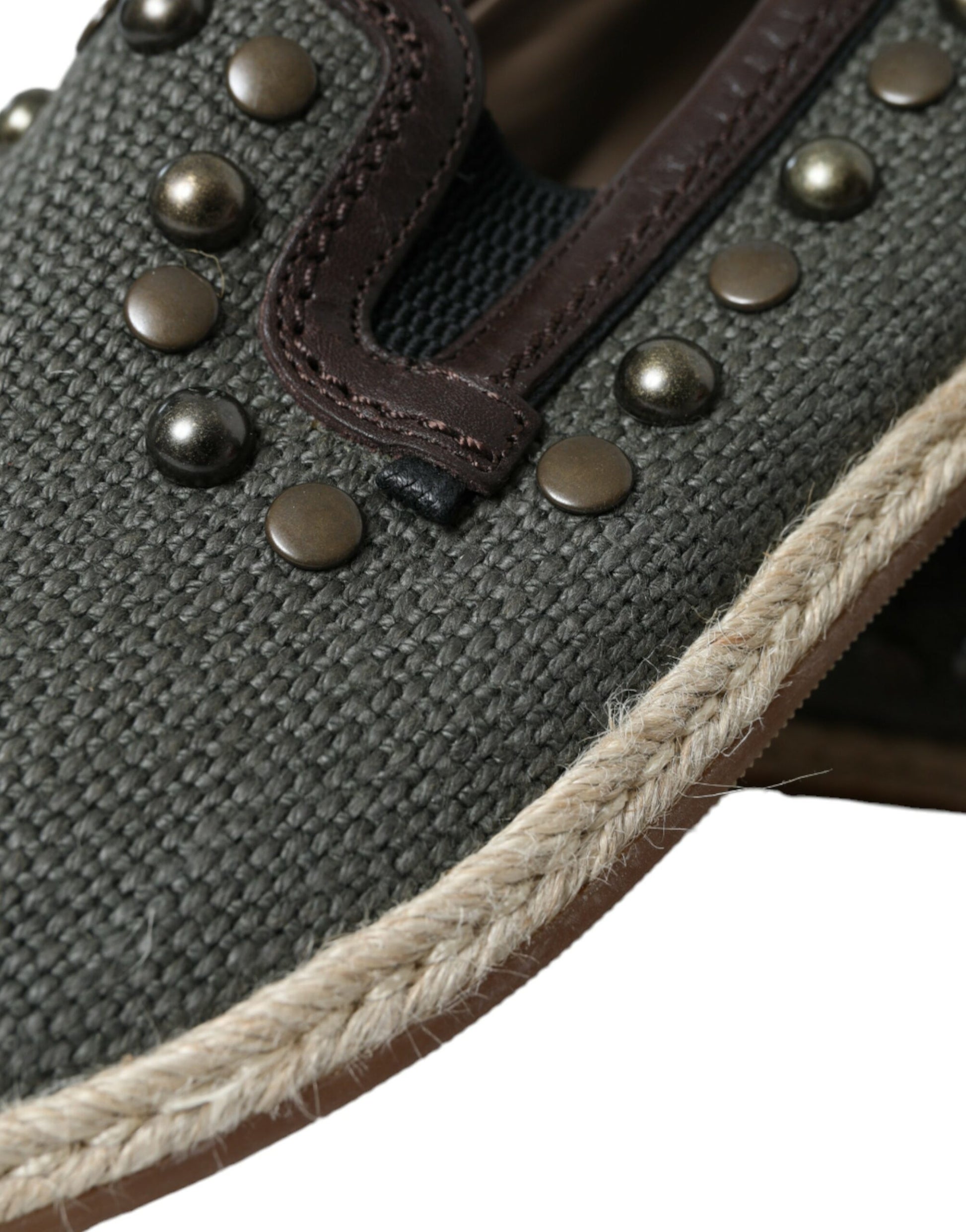Brown shoe with tan laces and black spikes on top of fabric
