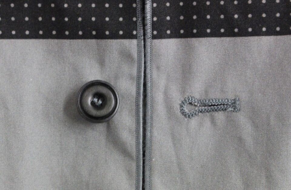 A gray vest with black polka dots, part of a dress ensemble
