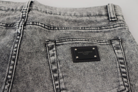 Pair of light blue denim jeans with a small rectangular metal plaque on the right side of the waistband