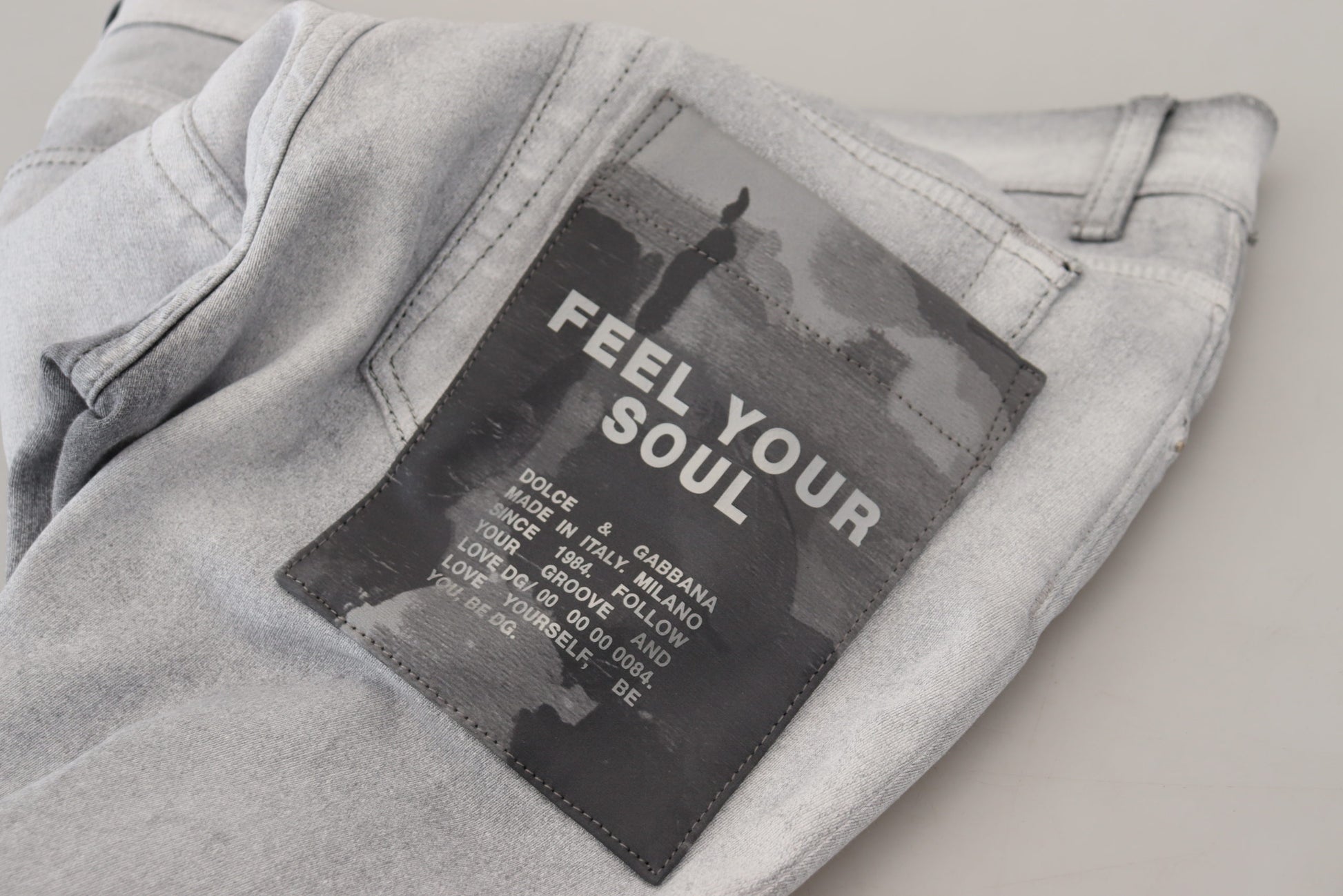 Pair of light blue jeans with a black patch on the back that says "Feel Your Soul"
