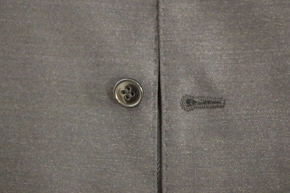 A gray vest with a button closure and a black label on the inside