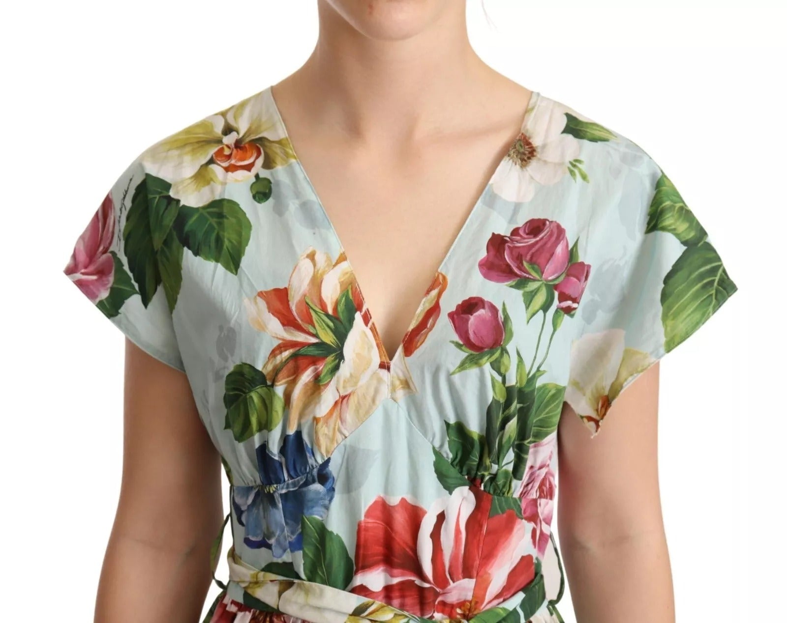 A woman wearing a green floral dress with short sleeves and a V-neck
