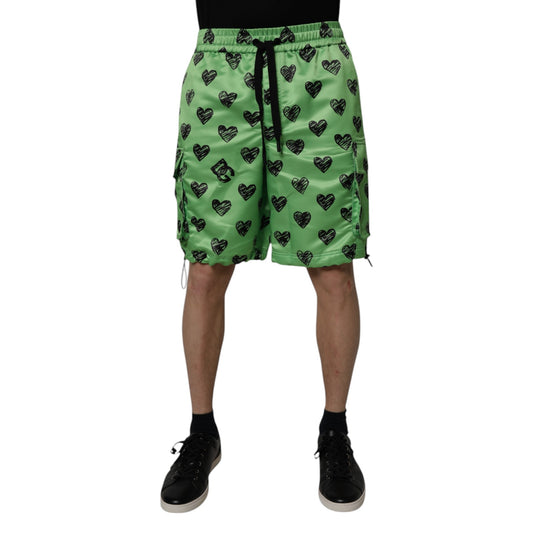 A pair of green men's shorts with a heart print design, featuring the brand name "Dolce & Gabbana" and the st