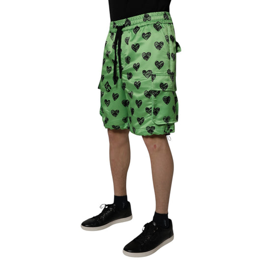 A pair of green men's shorts with a heart print design, featuring the brand name "Dolce & Gabbana