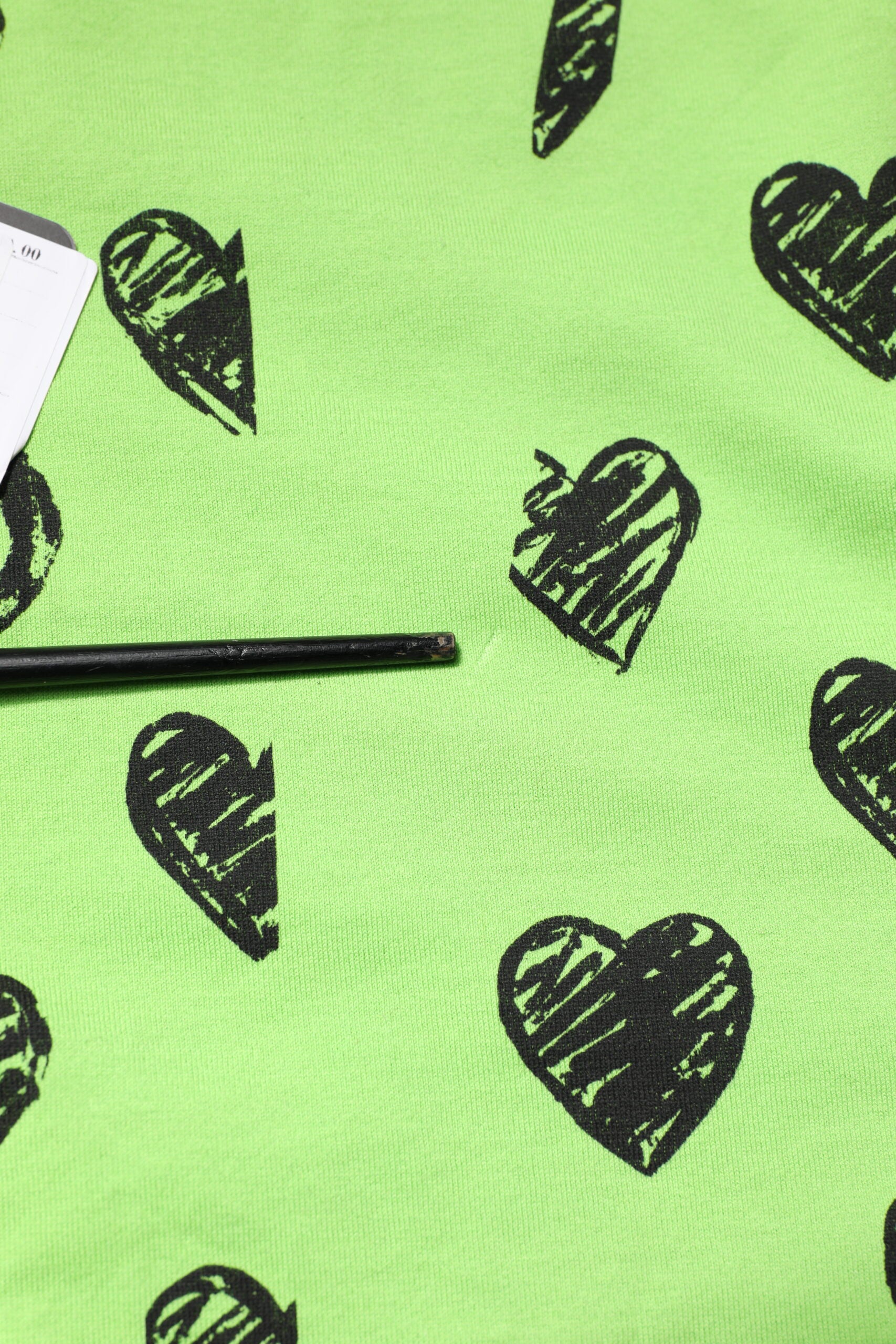 Green fabric with black hearts patterned on it
