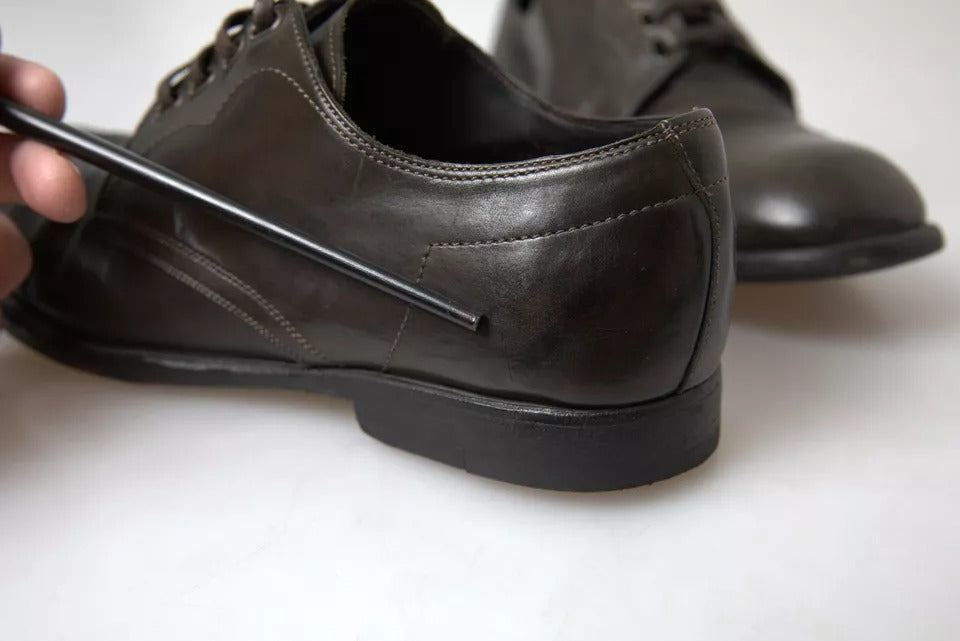 A pair of men's dress shoes with a green leather finish, featuring laces and a visible logo on the side