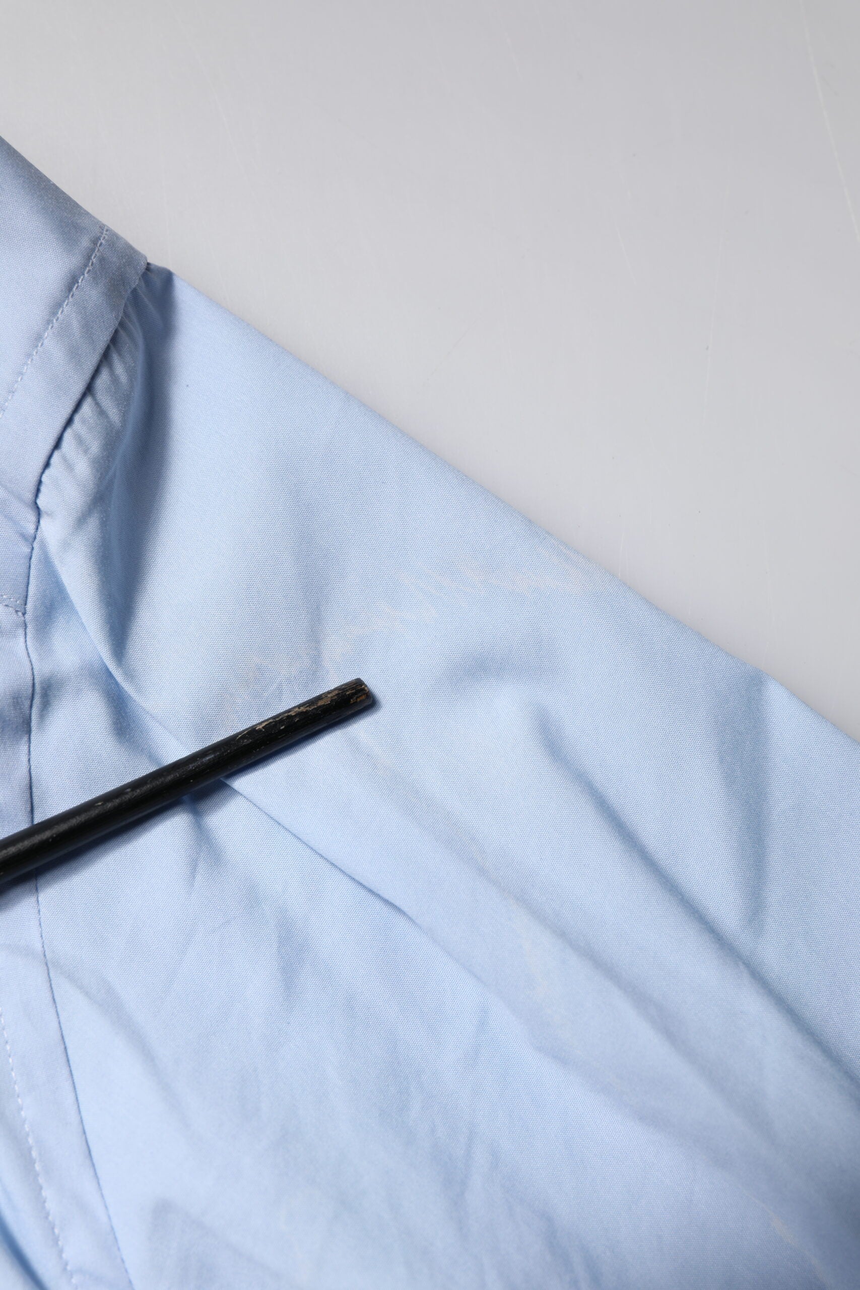 A light blue cotton dress shirt with a gold button and collar